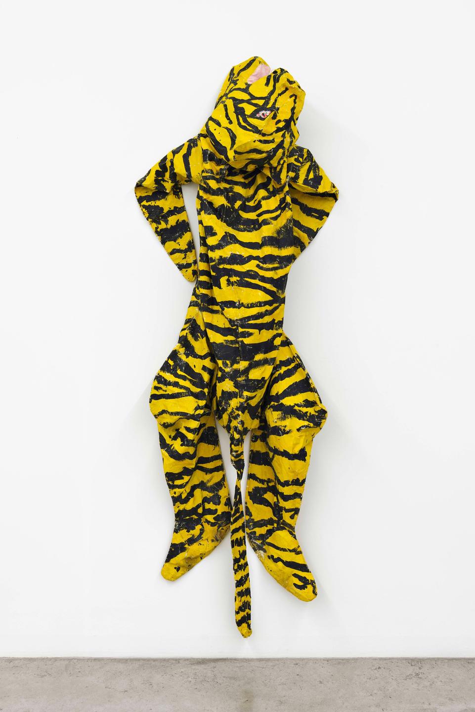 Ein Ganzkörper-Latexanzug mit einem Tigermuster hängt in einem Museum. Ein Ganzkörper-Latexanzug mit einem Tigermuster hängt in einem Museum.