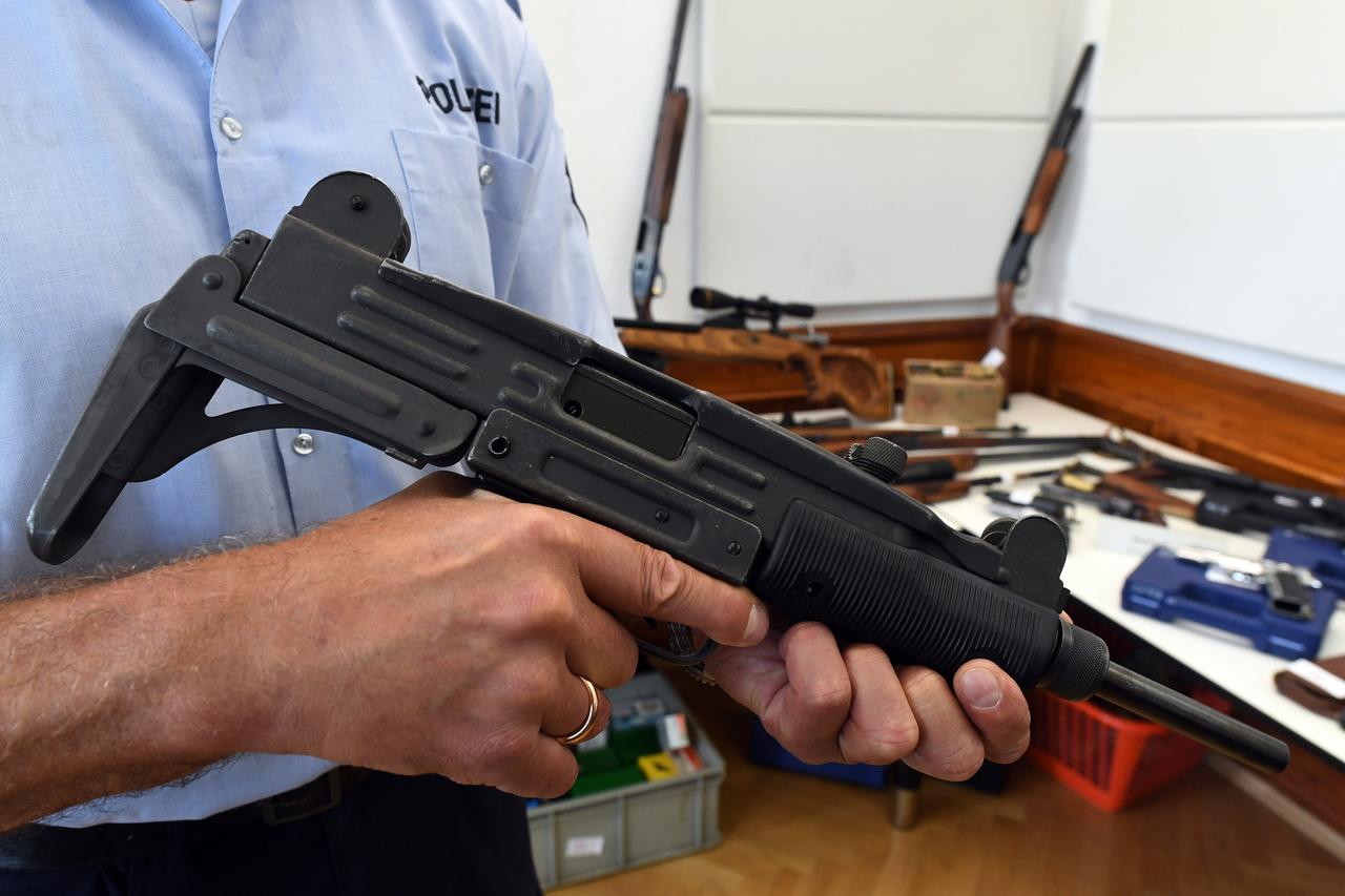 Ein Polizeibeamter hält eine beschlangnahmte Maschinenpistole vom Typ Uzi in den Händen
