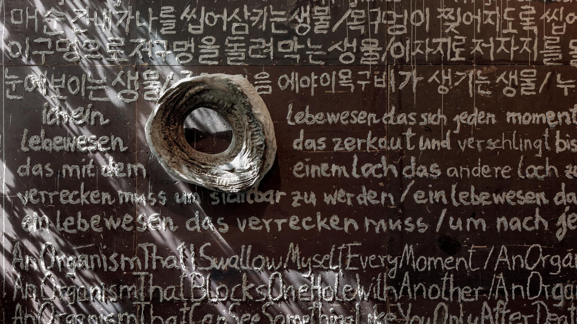 Blick in die Ausstellung im MMK: Ein auf die Wand mit einem in Flüssigbeton getauchten Zeigefinger geschriebenes Gedicht auf Deutsch, Englisch und Koreanisch. Blick in die Ausstellung im MMK: Ein auf die Wand mit einem in Flüssigbeton getauchten Zeigefinger geschriebenes Gedicht auf Deutsch, Englisch und Koreanisch.