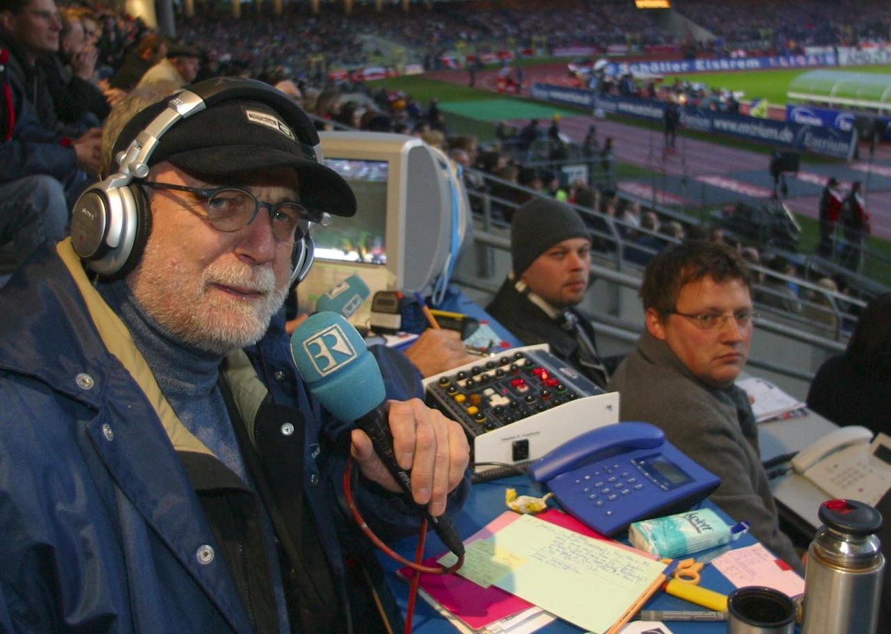 Günther Koch sitzt mit Kopfhörern und Mikrofon auf der Pressetribüne im Stadion Günther Koch sitzt mit Kopfhörern und Mikrofon auf der Pressetribüne im Stadion