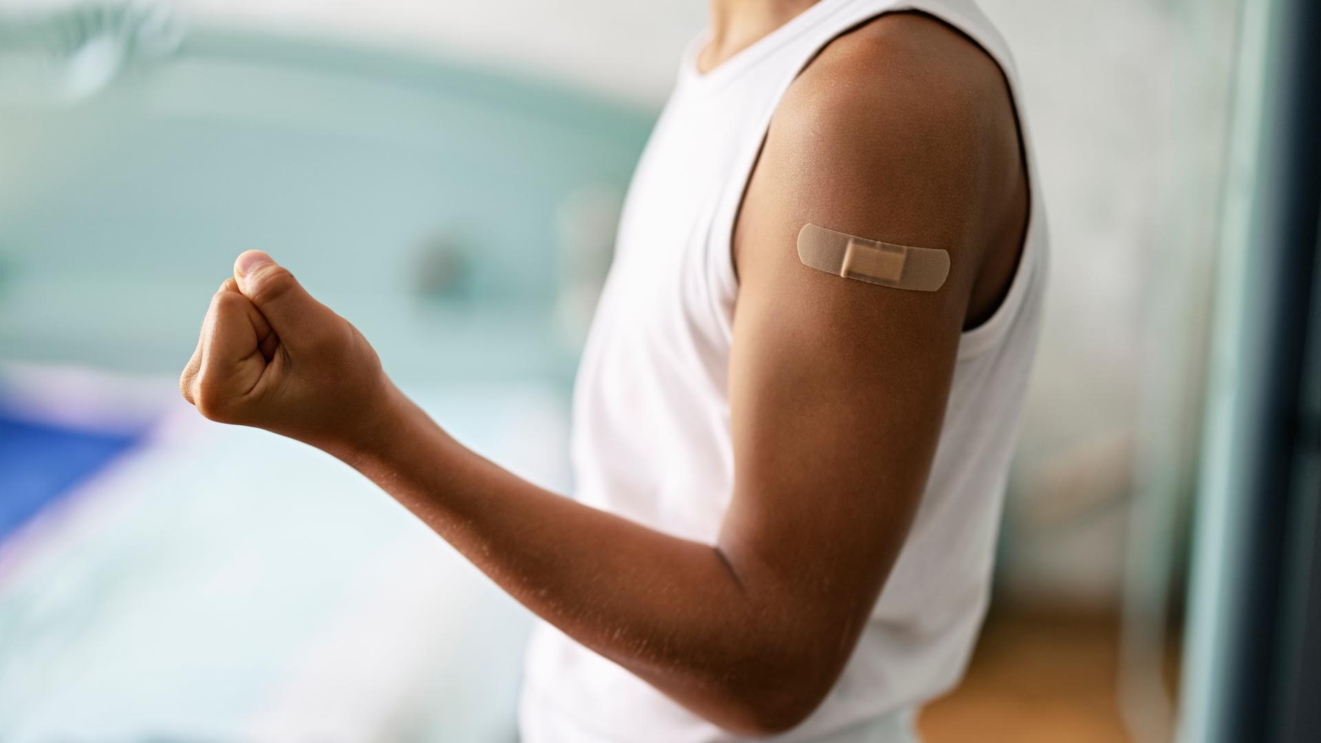 Ein Teenager zeigt stolz sein Pflaster am Oberarm nach der Impfung.
