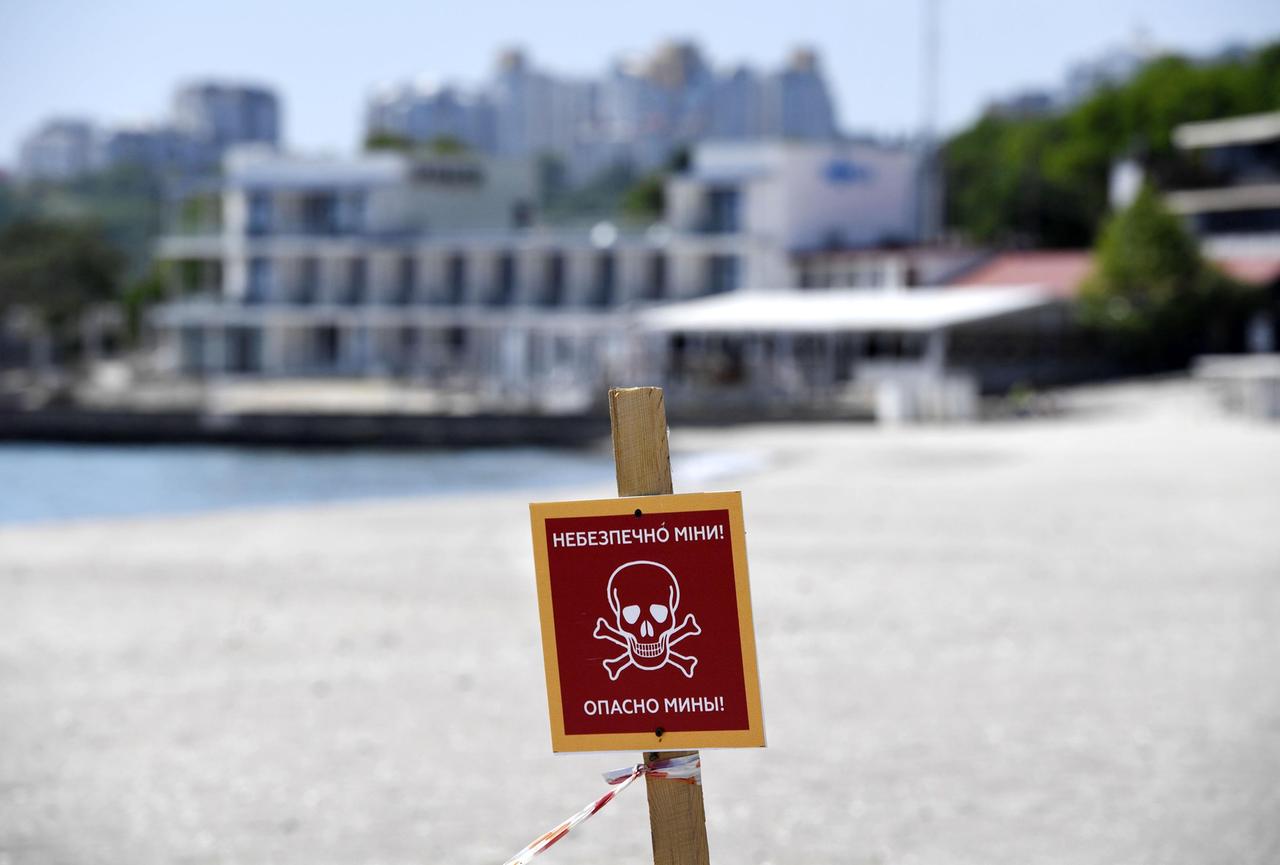 Ein Schild an einem Strand in Odessa in der südlichen Ukraine warnt vor Landminen. Im Hintergrund sind Gebäude zu sehen. Ein Schild an einem Strand in Odessa in der südlichen Ukraine warnt vor Landminen. Im Hintergrund sind Gebäude zu sehen.