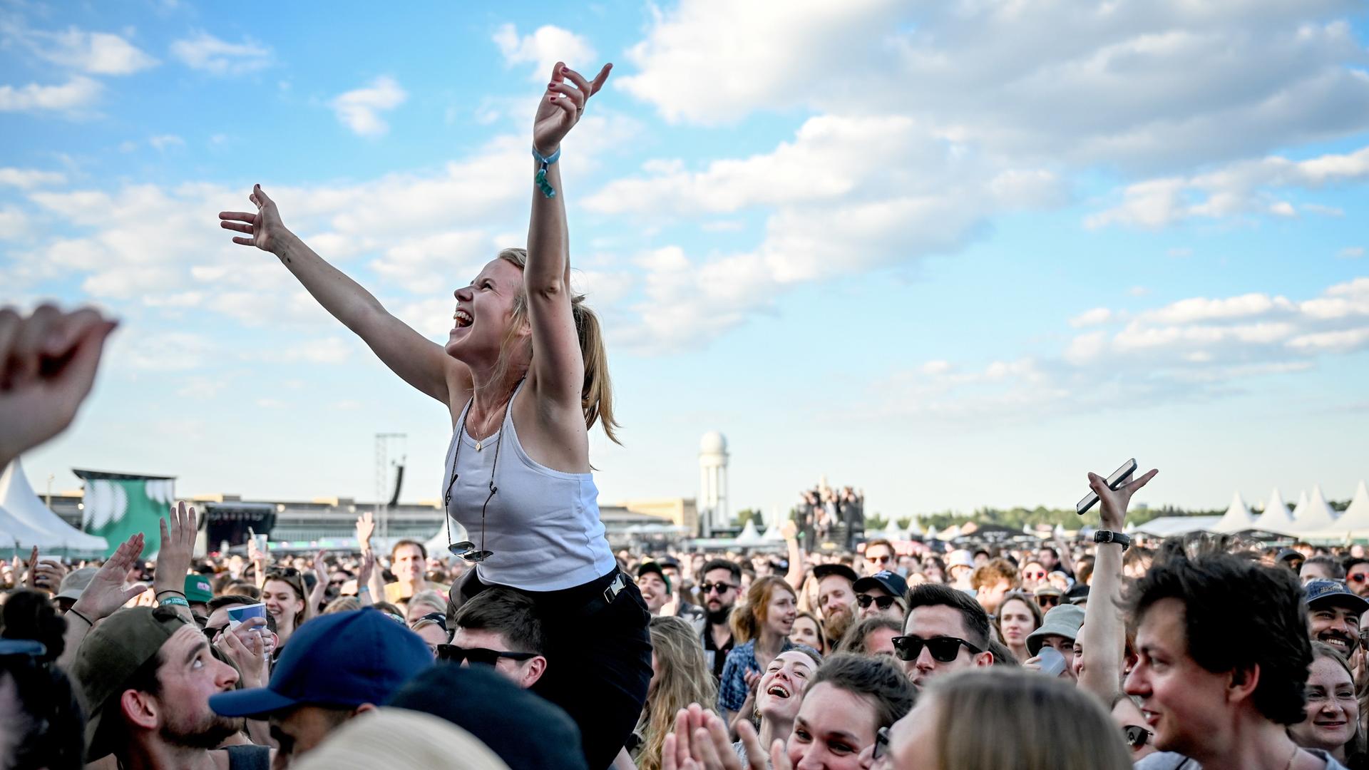 Das Publikum feiert beim Tempelhof-Sounds Festival auf dem Gelände des ehemaligen Flughafen Berlin Tempelhof. Eine junge Frau ist auf den Schultern eines anderen Besuchers und freut sich. Das Publikum feiert beim Tempelhof-Sounds Festival auf dem Gelände des ehemaligen Flughafen Berlin Tempelhof. Eine junge Frau ist auf den Schultern eines anderen Besuchers und freut sich.