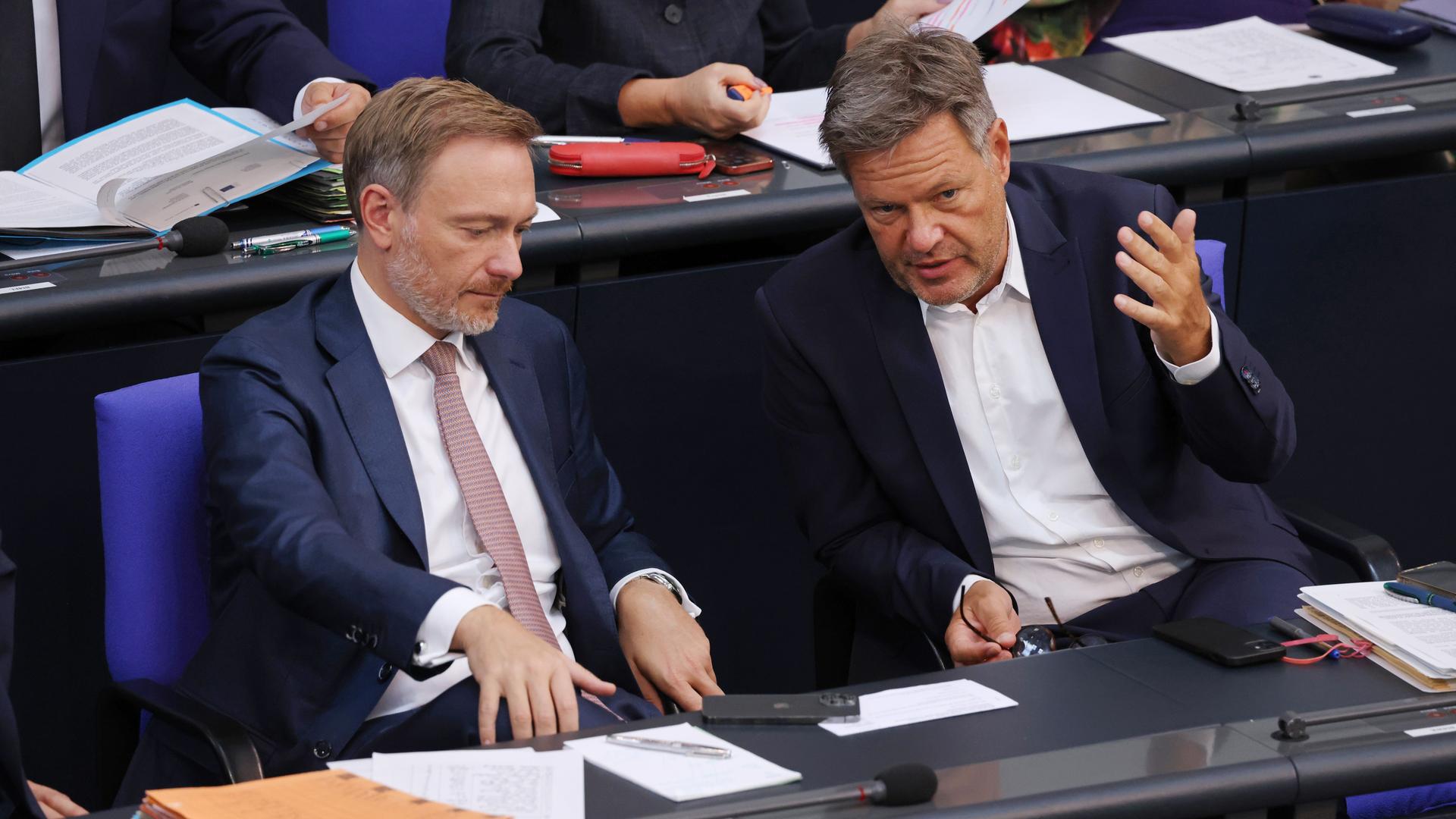 Robert Habeck und Christian Lindner sitzen bei einer Bundestagsdebatte nebeneinander. Habeck redet und gestikuliert mit den Händen, Lindner hört zu. Robert Habeck und Christian Lindner sitzen bei einer Bundestagsdebatte nebeneinander. Habeck redet und gestikuliert mit den Händen, Lindner hört zu.
