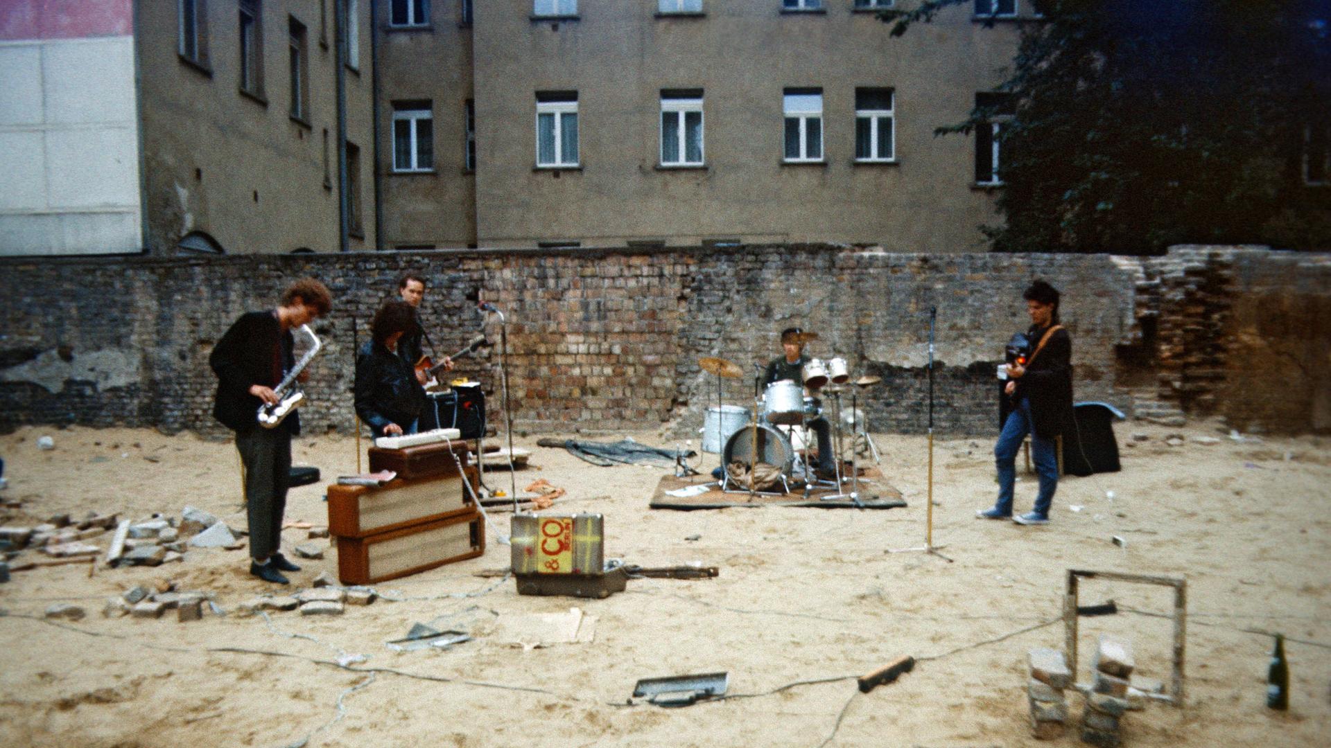Privat organisiertes Punkkonzert in einem Ostberliner Hinterhof im Mai 1985. Vier Musiker spielen und singen in einem leeren Hinterhof vor einer bröckelnden Mauer. Privat organisiertes Punkkonzert in einem Ostberliner Hinterhof im Mai 1985. Vier Musiker spielen und singen in einem leeren Hinterhof vor einer bröckelnden Mauer.