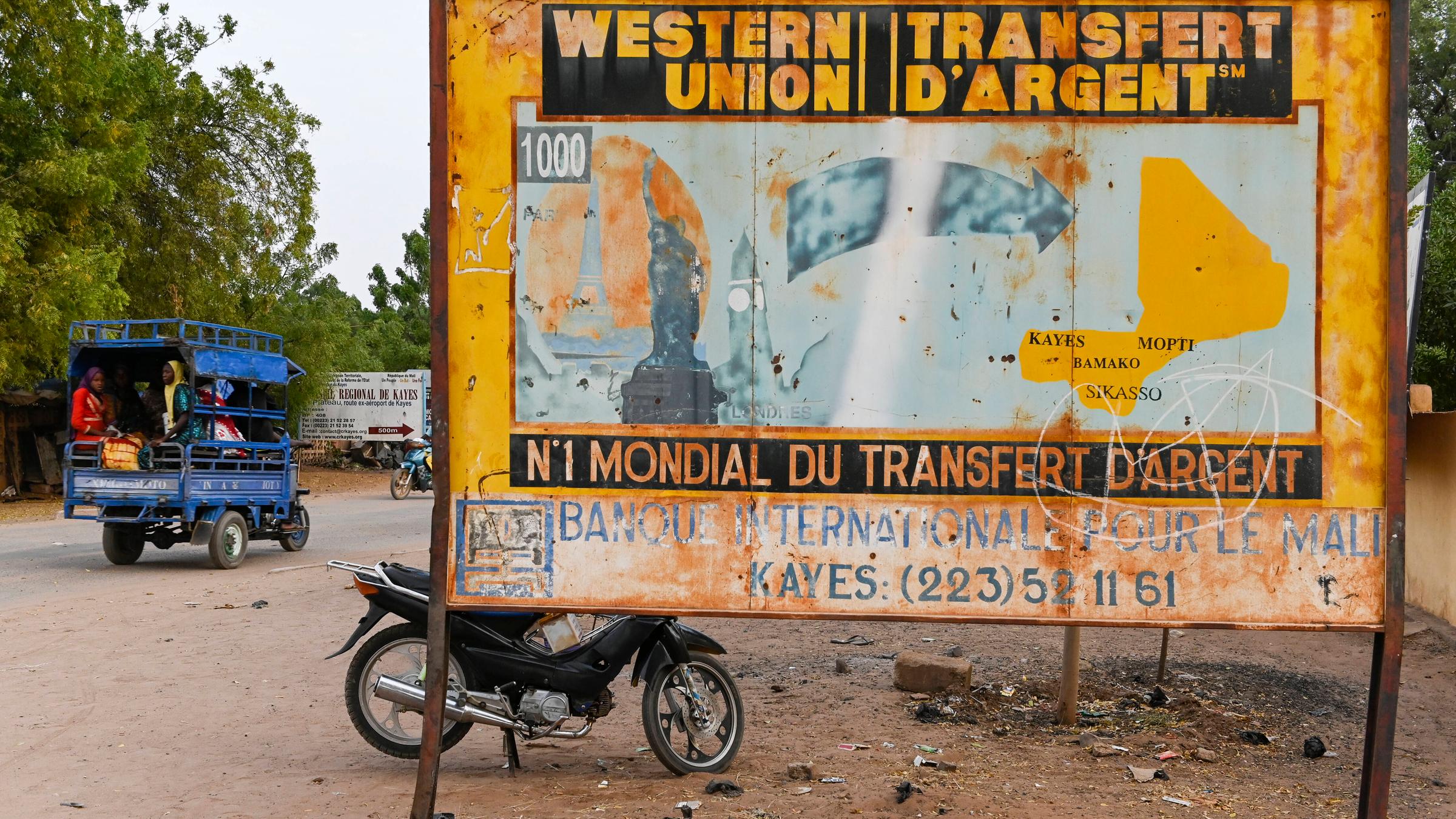 Altes Schild von Western Union in Mali. Es zeigt eine Illustration von Wahrzeichen westlicher Städte, von denen ein Pfeil nach Mali führt.