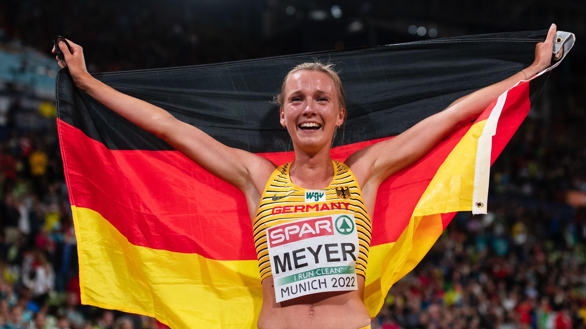 Lea Meyer jubelt im Ziel und hält die Deutschland-Flagge.
