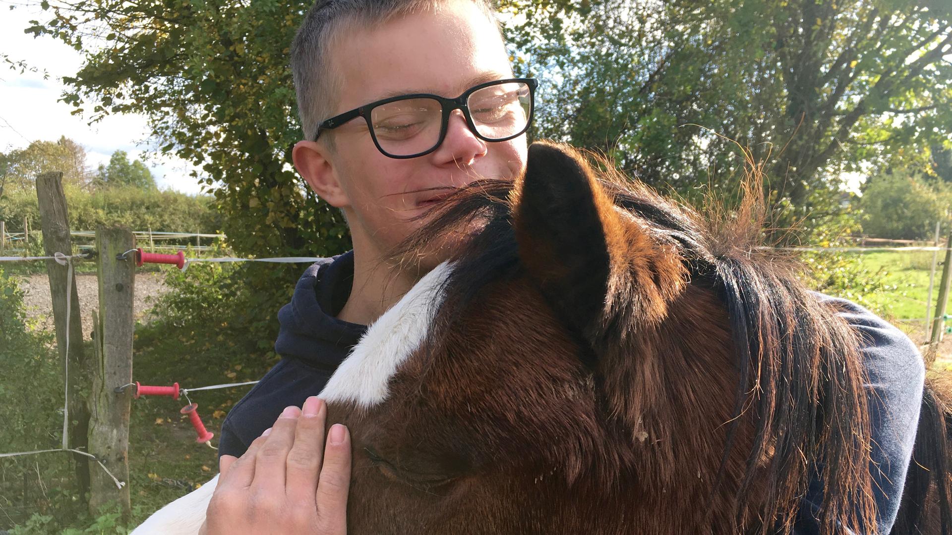 Ein Junge mit Down-Syndrom herzt ein Pferd. Ein Junge mit Down-Syndrom herzt ein Pferd.
