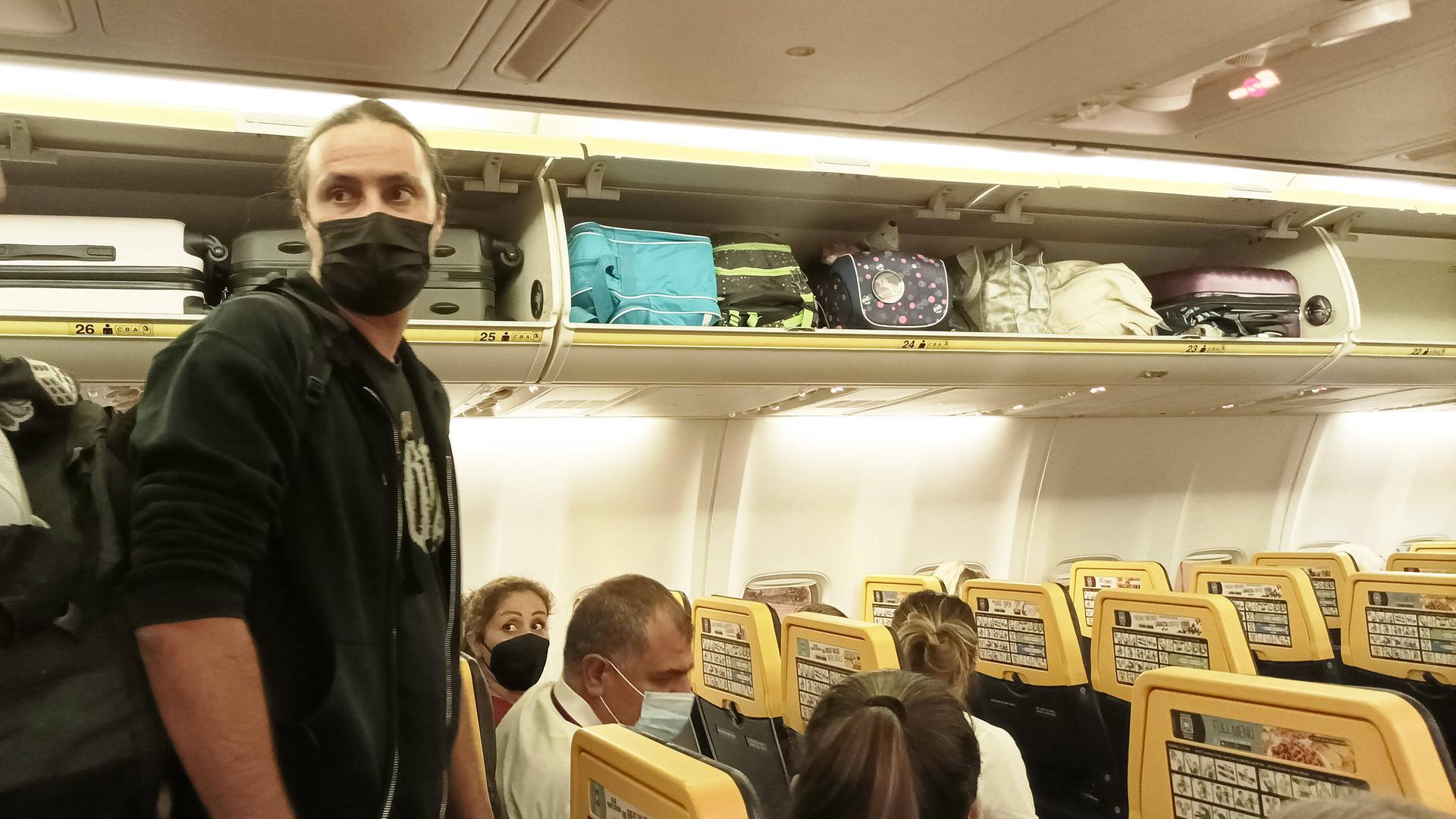 Reisende mit Masken in einem Flugzeug. Die Maskenpflicht soll künftig wegfallen