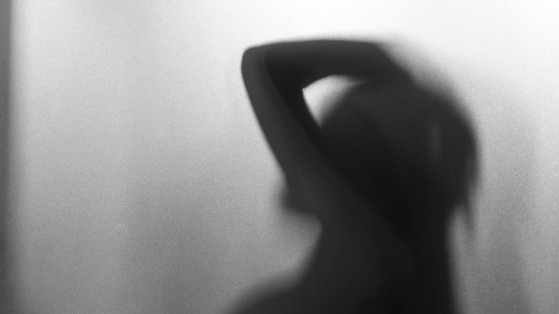 Die Silhouette einer weiblichen Person hinter eine Milchglasscheibe. Die Silhouette einer weiblichen Person hinter eine Milchglasscheibe.