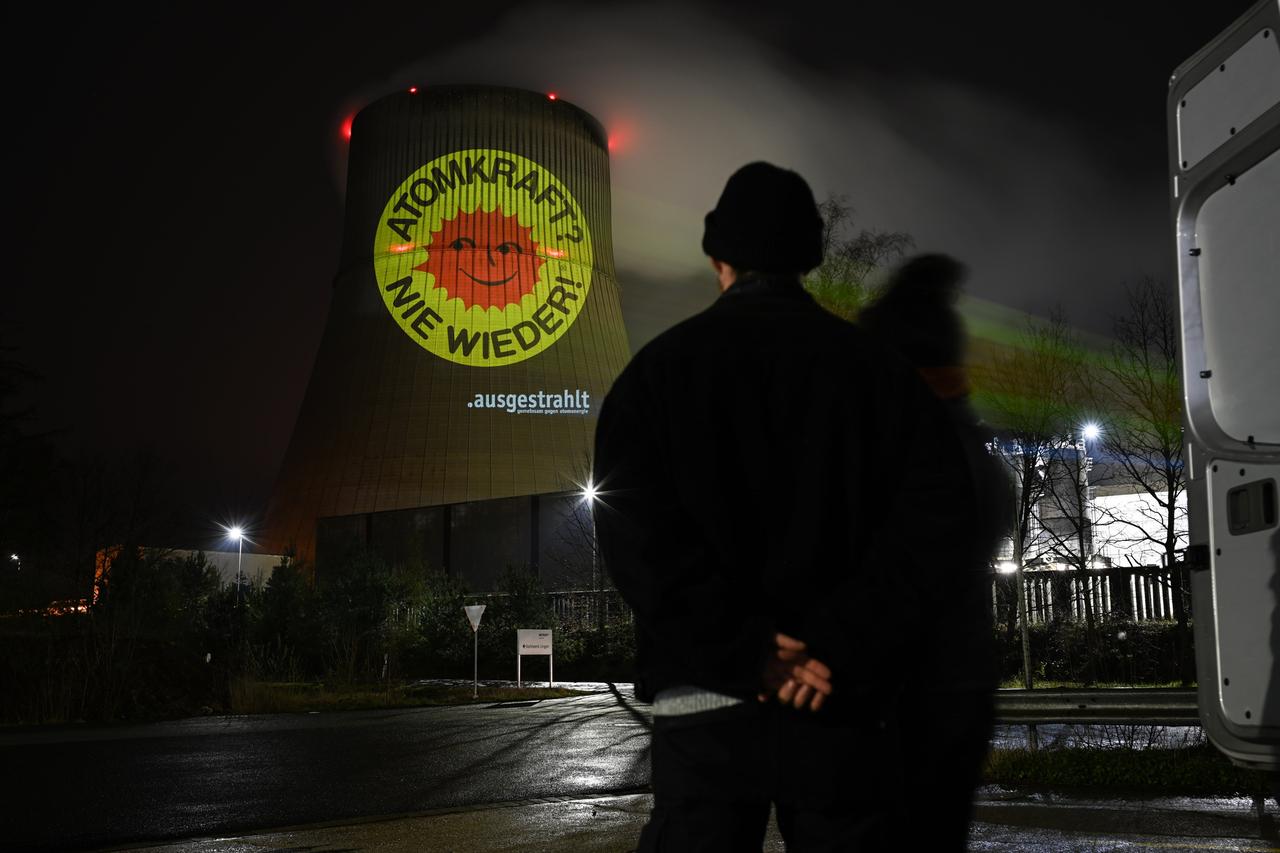 Aktivisten der Anti-Atom-Bewegung projizieren eine große Anti-Atom-Sonne auf den Kühlturm des Atomkraftwerkes Emsland. Anlass ist die Abschaltung der letzten AKW am 15. April. 