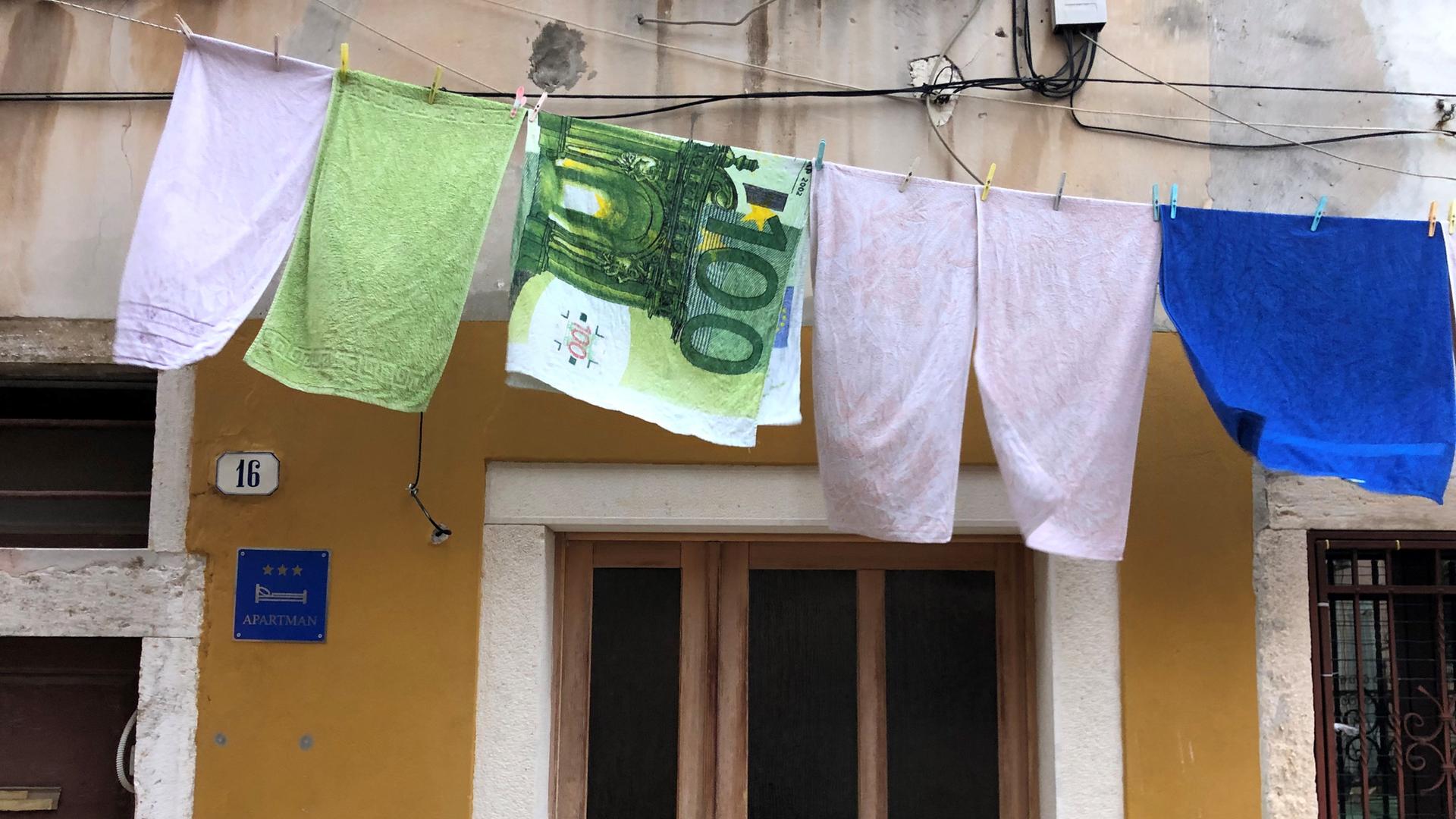 Auf eine Wäscheleine hängt eun Handtuch mit Euroschein Motiv