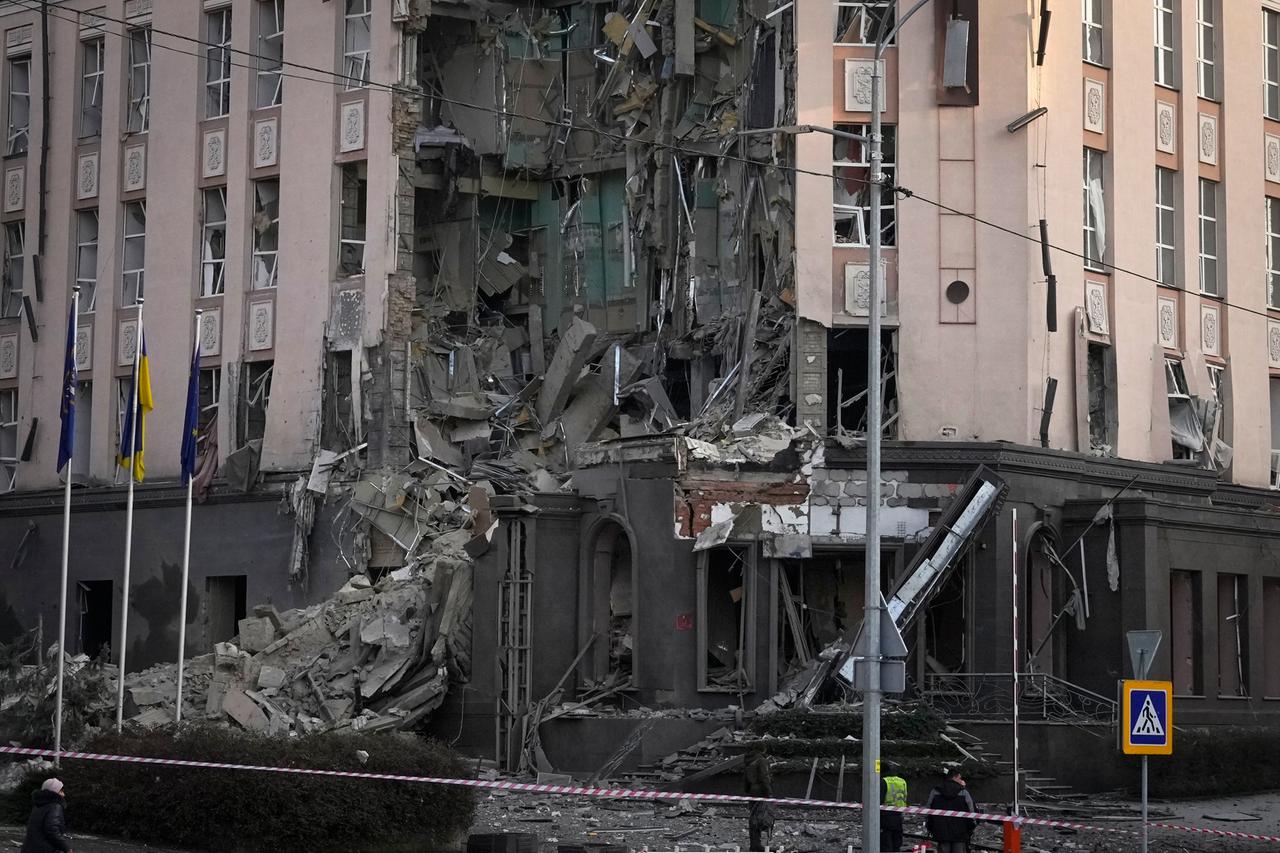 Polizisten stehen vor einem durch Beschuss beschädigten Haus. Polizisten stehen vor einem durch Beschuss beschädigten Haus.