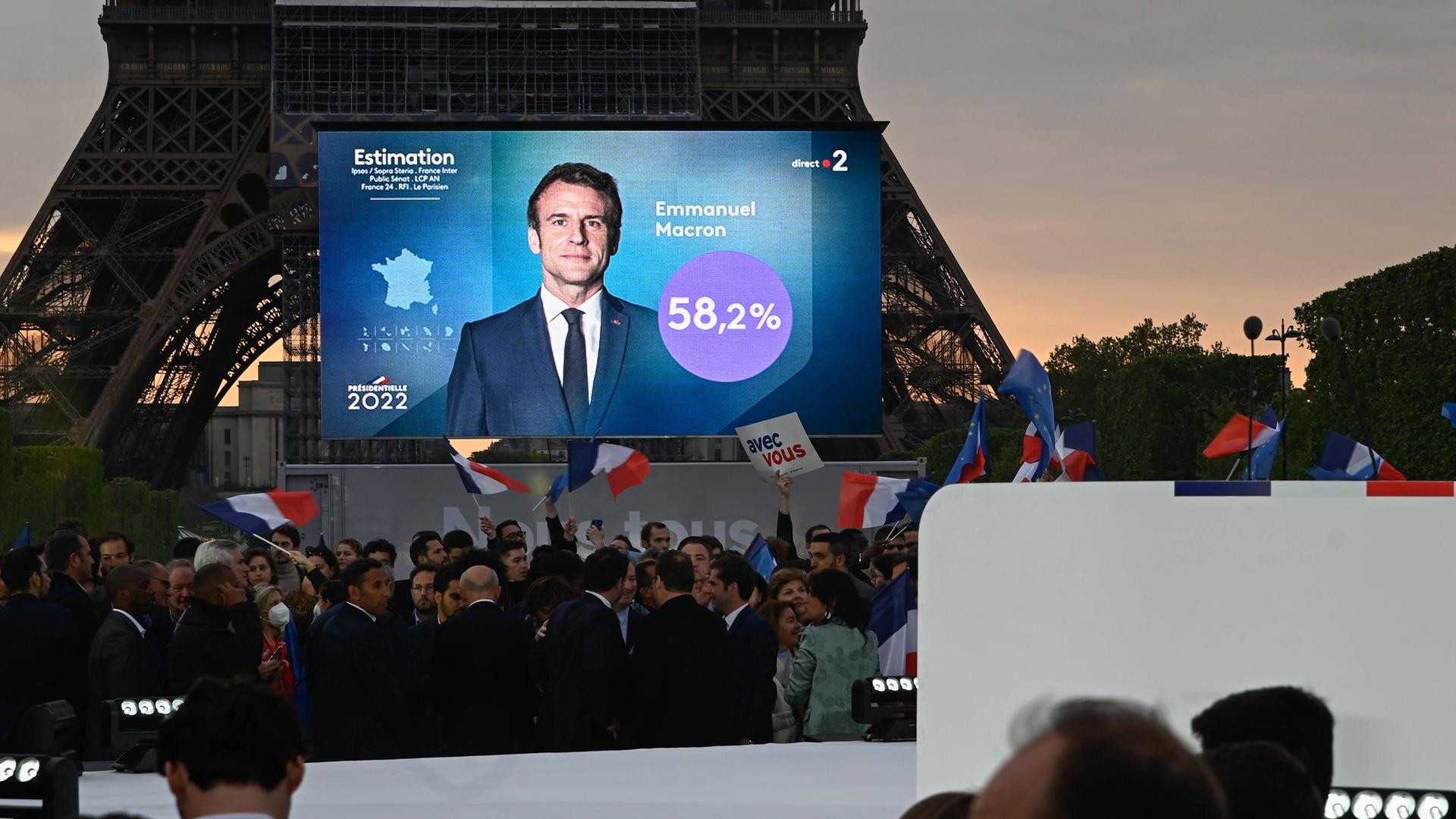 Auf einer Bühne Champs de Mars in Paris ist die Ankündigung auf einer Leinwand zu sehen, dass Emmanuel Macron die Wahl gewonnen hat. 