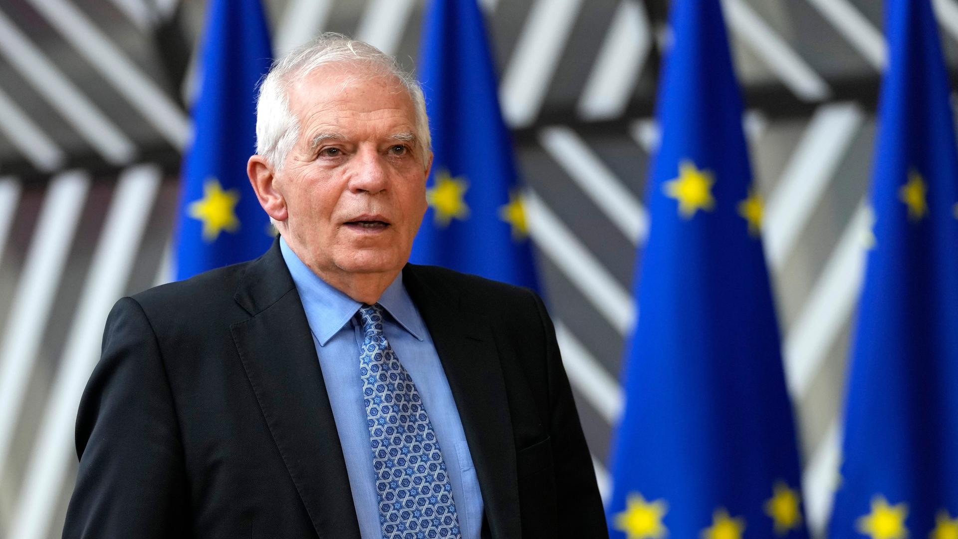 Josep Borrell steht in Brüssel vor mehreren EU-Flaggen.