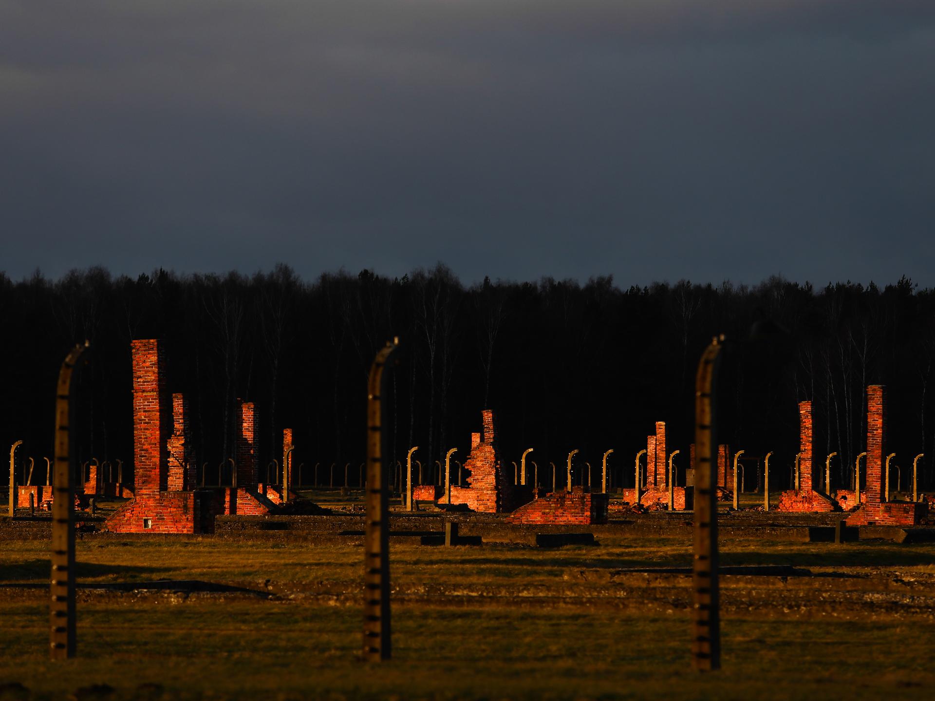 Blick auf das Lagergelände des ehemaligen deutschen nationalsozialistischen Konzentrationslages Auschwitz II-Birkenau in Brzezinka bei Oswiecim, Polen, am 3. Januar 2022. Zu sehen sind die Reste der zerstörten Baracken hinter Stacheldrahtumzeunung im Abendlicht.