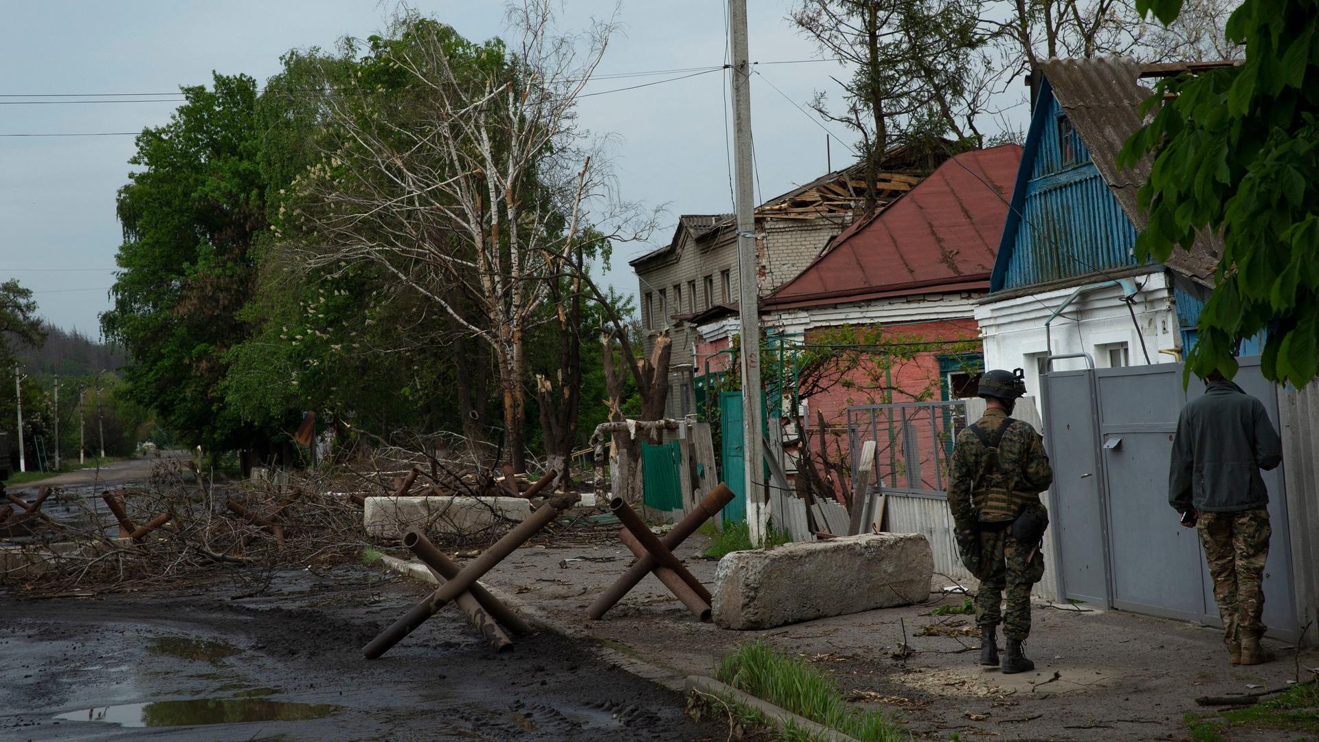 Zwei Soldaten gehen an einer Straße in der Nähe der Stadt Isjum entlang, auf der Sperren aufgebaut sind.