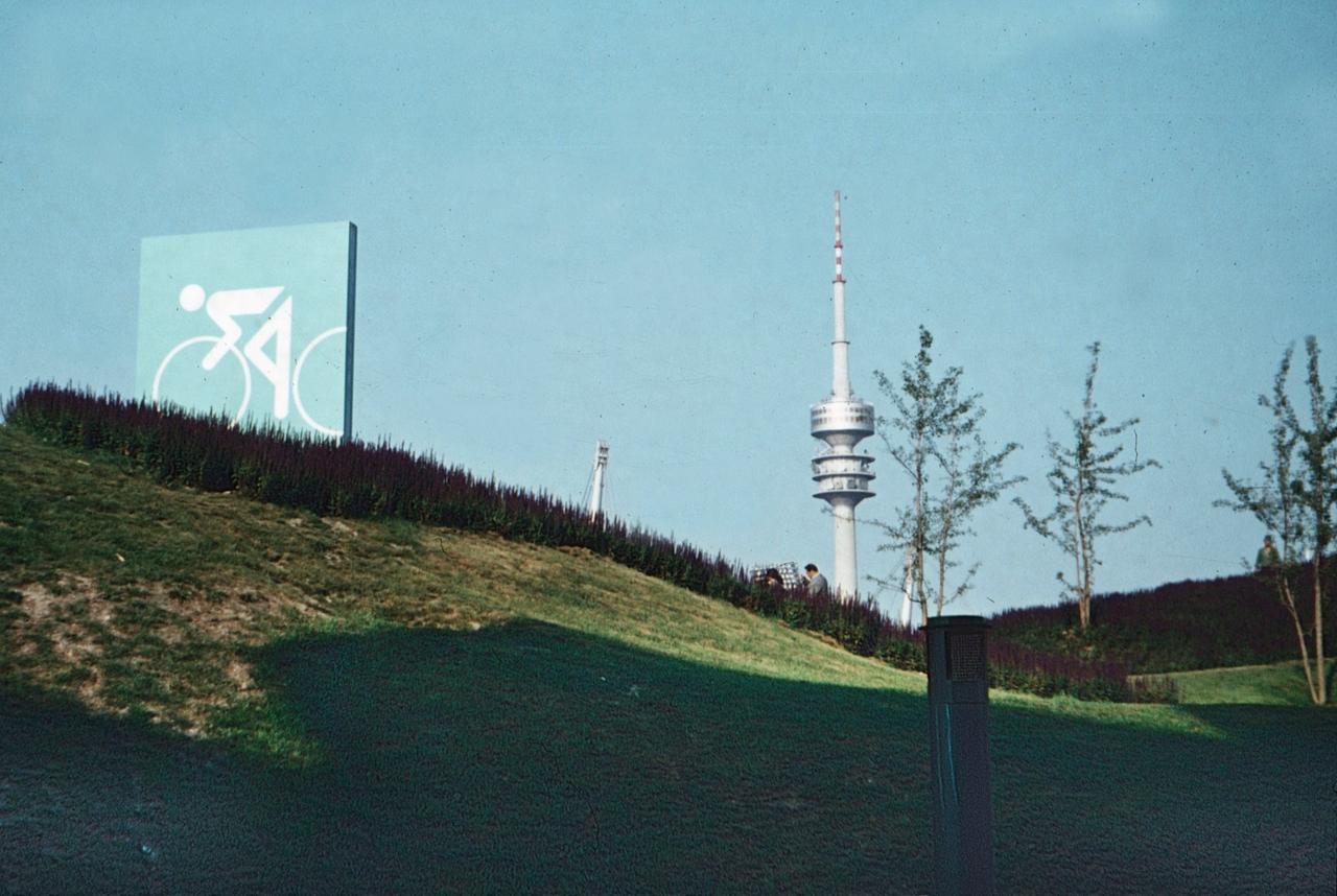 Der Olympiapark 1972: grüner Hügel mit dem Hinweisschild zum Radstadion.