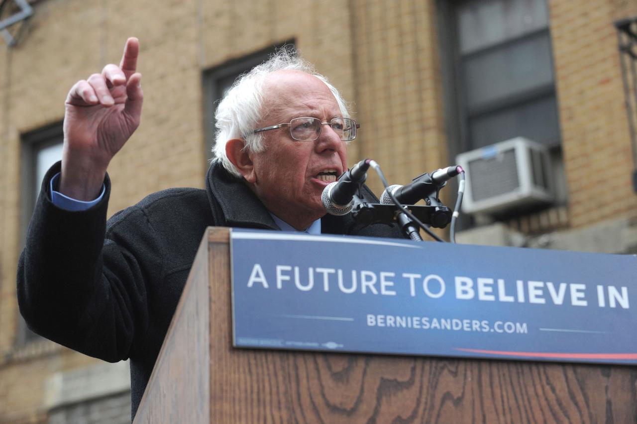 Bernie Sanders am Rednerpult, daran ist ein Schild mit der Aufschrift "A future to believe in - berniesanders.com" befestigt. Bernie Sanders am Rednerpult, daran ist ein Schild mit der Aufschrift "A future to believe in - berniesanders.com" befestigt.