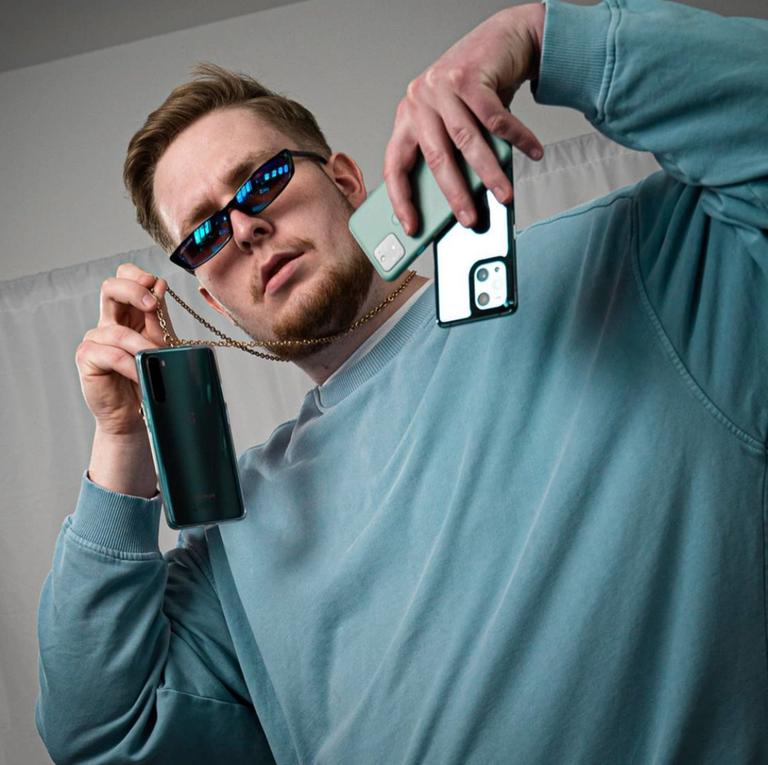 Ein Mann hält drei Smartphones in die Kamera. Ein Mann hält drei Smartphones in die Kamera.