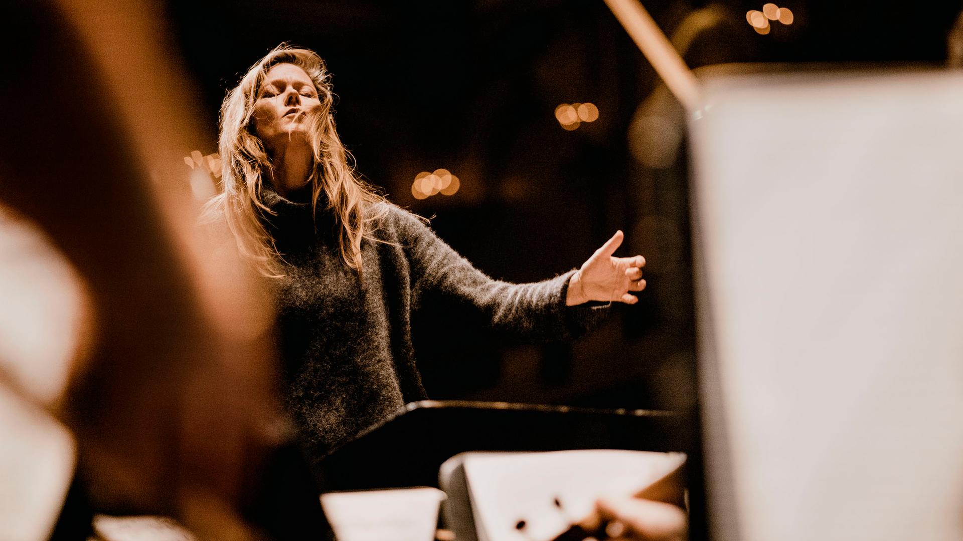 Barbara Hannigan dirigiert ein Orchester mit geschlossenen Augen und legt in diesem Moment den Kopf ein wenig nach hinten. Barbara Hannigan dirigiert ein Orchester mit geschlossenen Augen und legt in diesem Moment den Kopf ein wenig nach hinten.