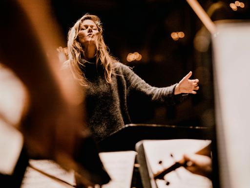 Barbara Hannigan dirigiert ein Orchester mit geschlossenen Augen und legt in diesem Moment den Kopf ein wenig nach hinten.