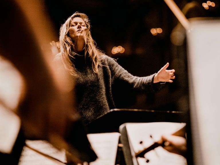 Barbara Hannigan dirigiert ein Orchester mit geschlossenen Augen und legt in diesem Moment den Kopf ein wenig nach hinten.