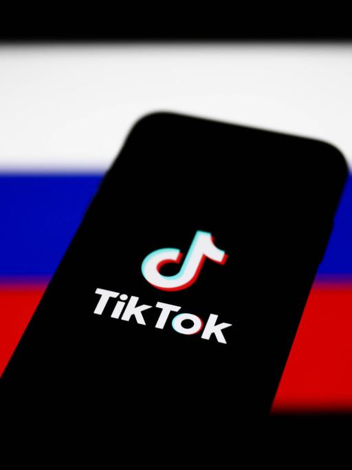 Ein Smartphone mit dem Logo von TikTok vor dem Hintergrund einer russischen Flagge 