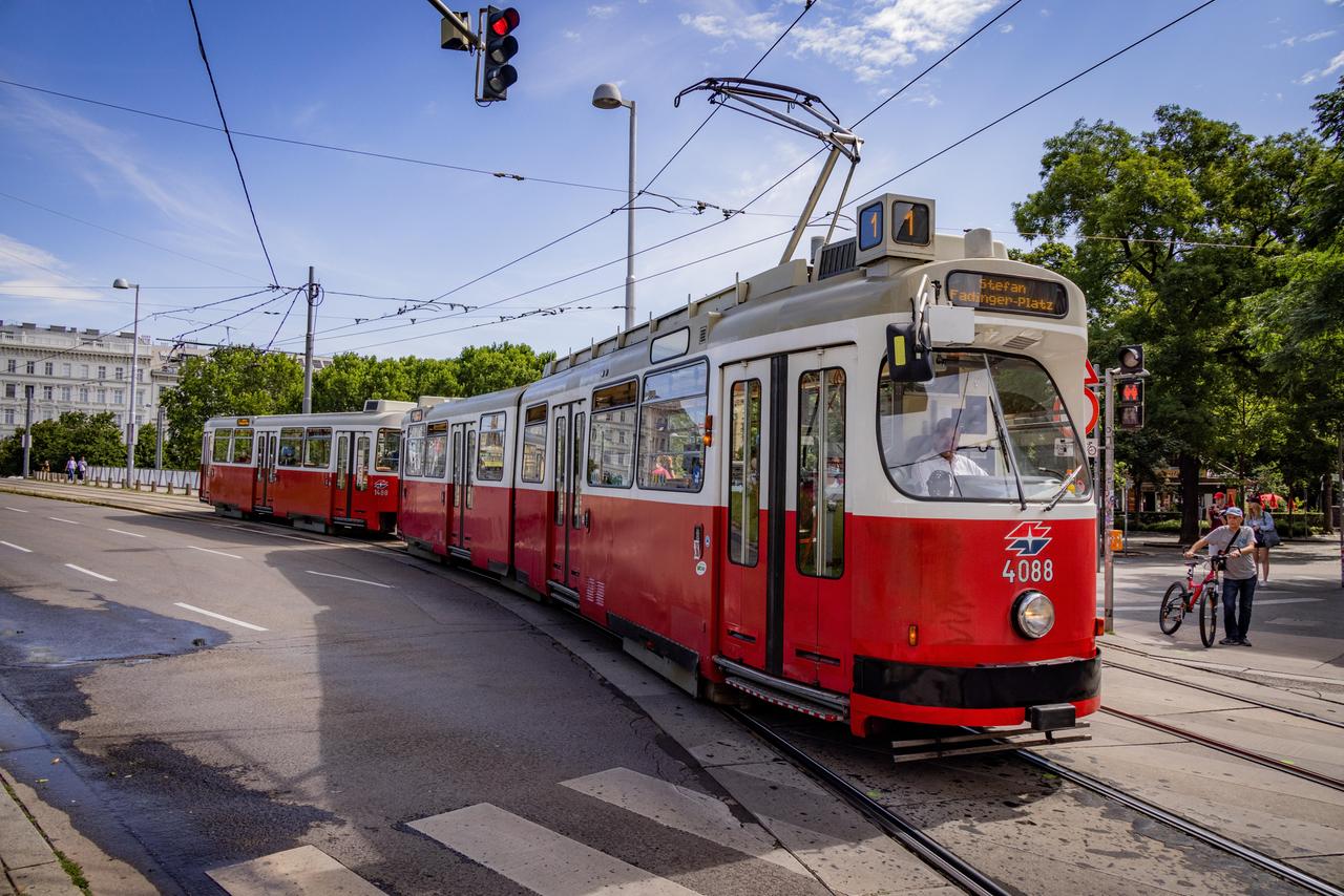 Eine rote Tram fährt durch die Straßen von Wien.