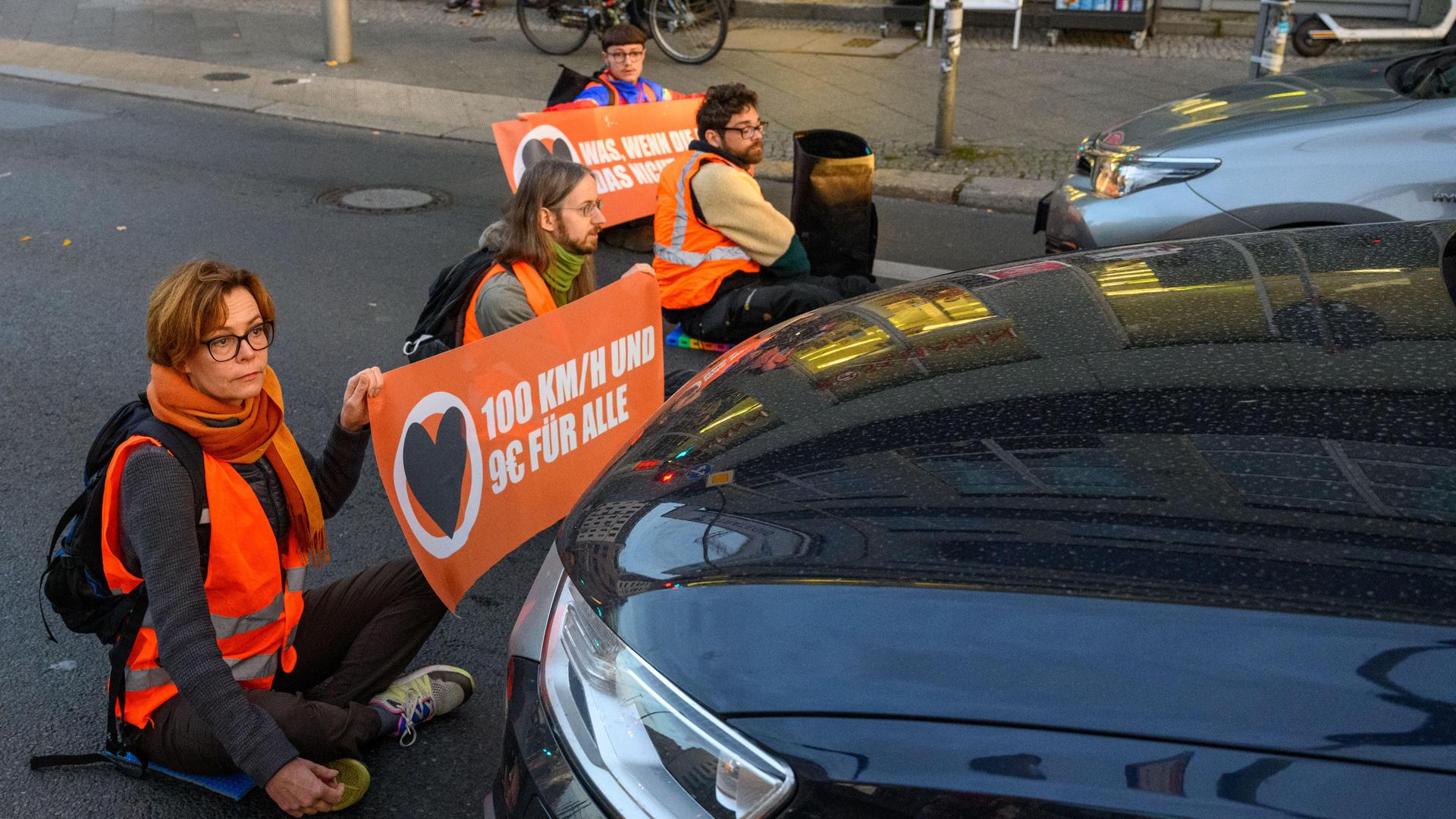 Aktivisten der Klimagruppe Aufstand der Letzten Generation blockieren sitzend eine Straße in Berlin.