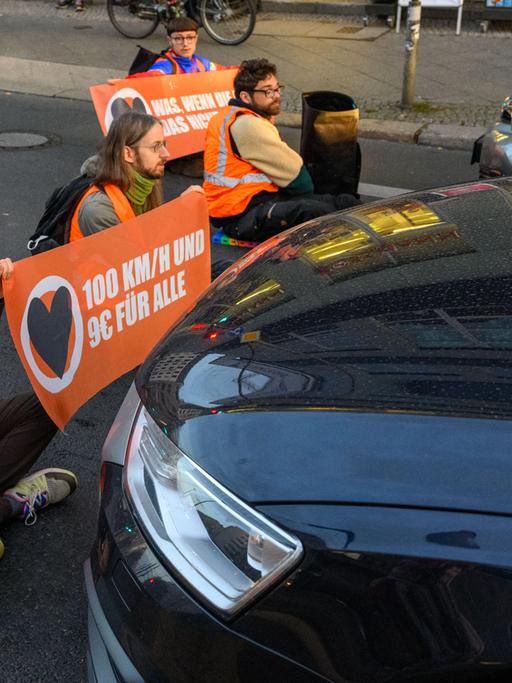 Aktivisten der Klimagruppe Aufstand der Letzten Generation blockieren sitzend eine Straße in Berlin.