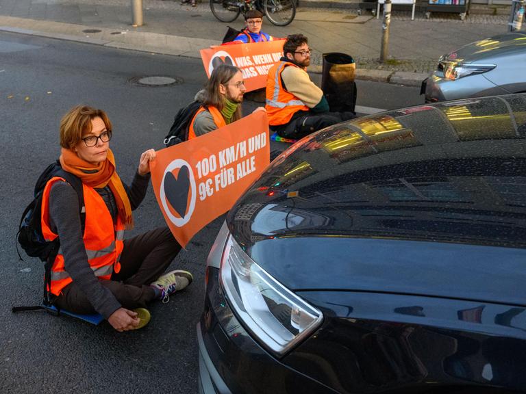 Aktivisten der Klimagruppe Aufstand der Letzten Generation blockieren sitzend eine Straße in Berlin.