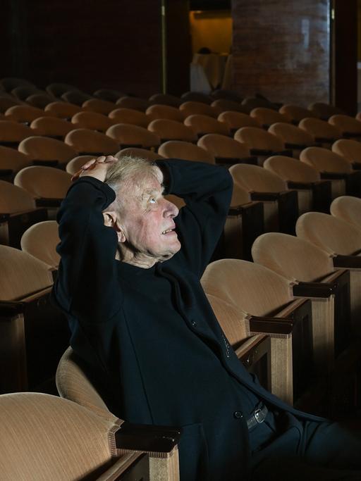 Der Theaterregisseur Claus Peymann sitzt im Zuschauerraum zwischen lauter leeren Stuhlreihen. 