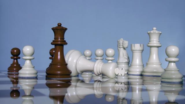 Der weiße König liegt geschlagen auf einem Schachbrett umgeben von weiteren Figuren