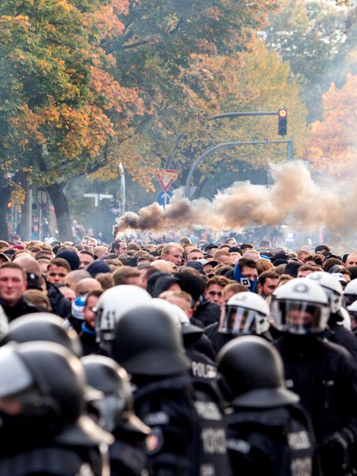 Die Fans des Hamburger SV gehen von der Polizei begleitet zum Stadion und brennen Pyrotechnik ab.