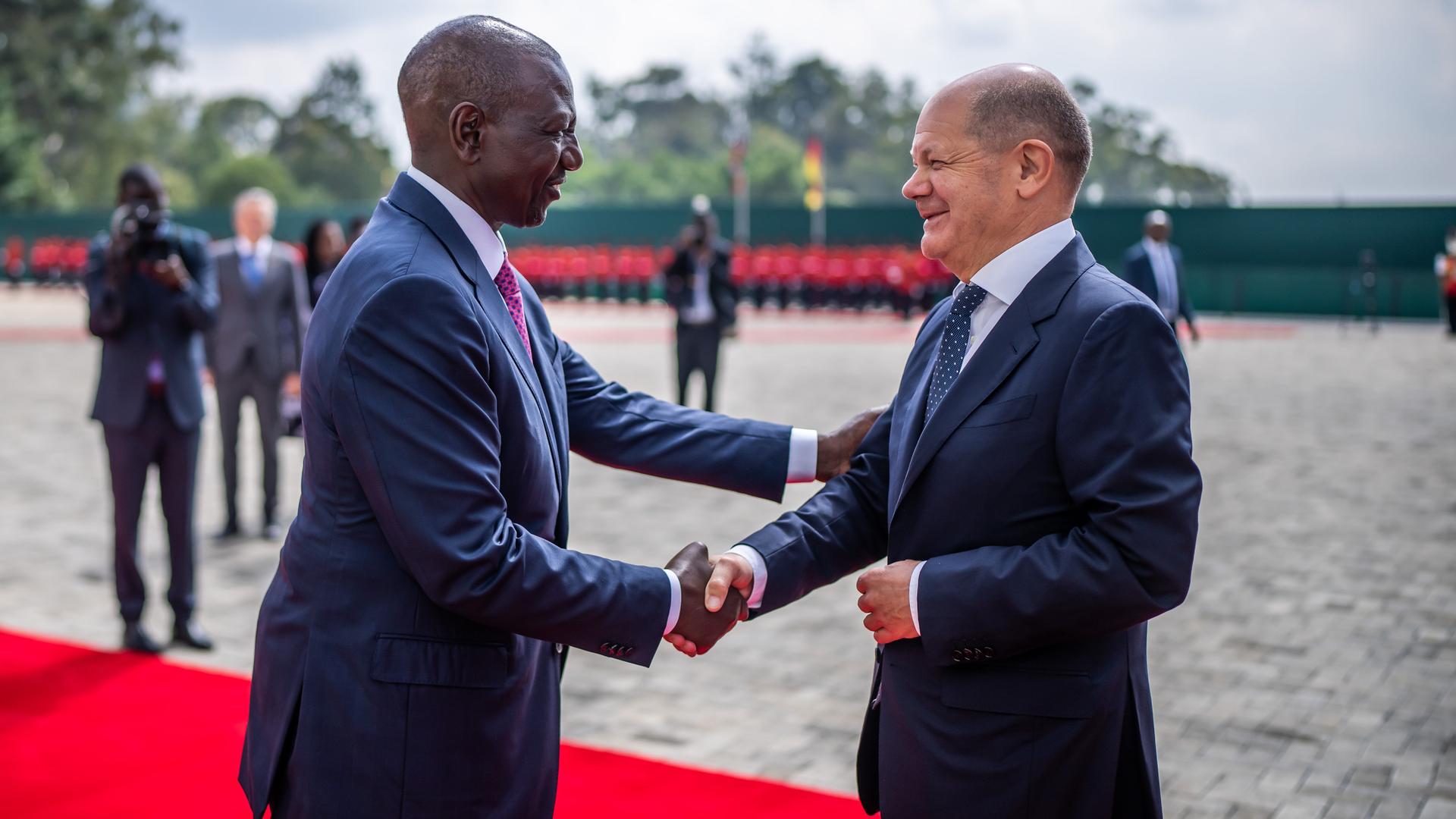 Nairobi: Bundeskanzler Olaf Scholz und William Ruto, Präsident von Kenia, schütteln sich die Hände. Sie stehen auf einem roten Teppich. Nairobi: Bundeskanzler Olaf Scholz und William Ruto, Präsident von Kenia, schütteln sich die Hände. Sie stehen auf einem roten Teppich.