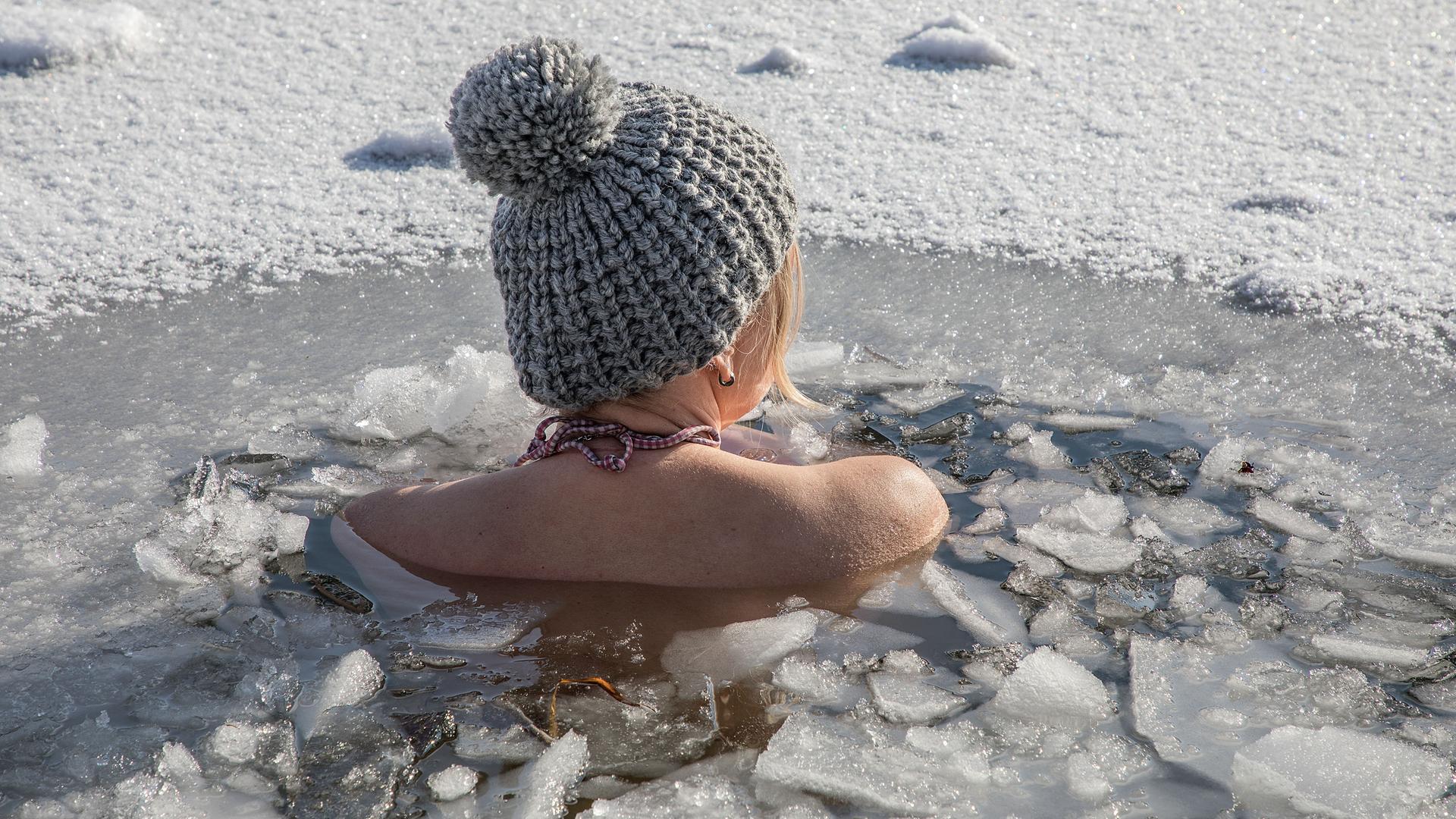 Eine Frau beim Eisbaden bei einer gefrorenen Wasserfläche im Winter, 2021. Eine Frau beim Eisbaden bei einer gefrorenen Wasserfläche im Winter, 2021.