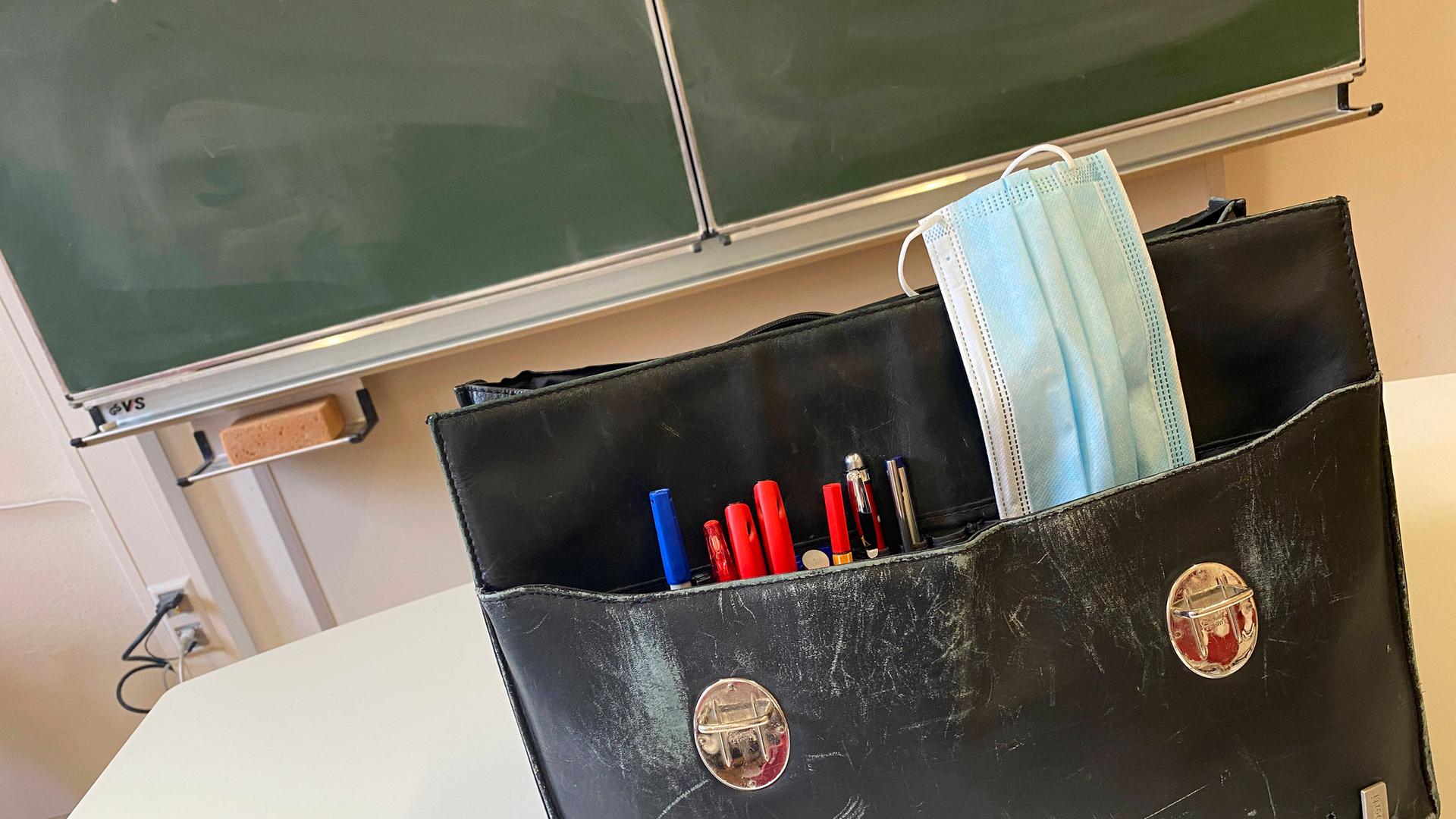 Die Tasche eines Lehrers steht auf dem Pult vor einer Tafel. Die Tasche eines Lehrers steht auf dem Pult vor einer Tafel.