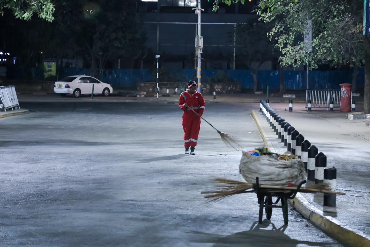 Ein Straßenreiniger putzt während der nächtlichen Ausgangssperre die Straße in Nairobi