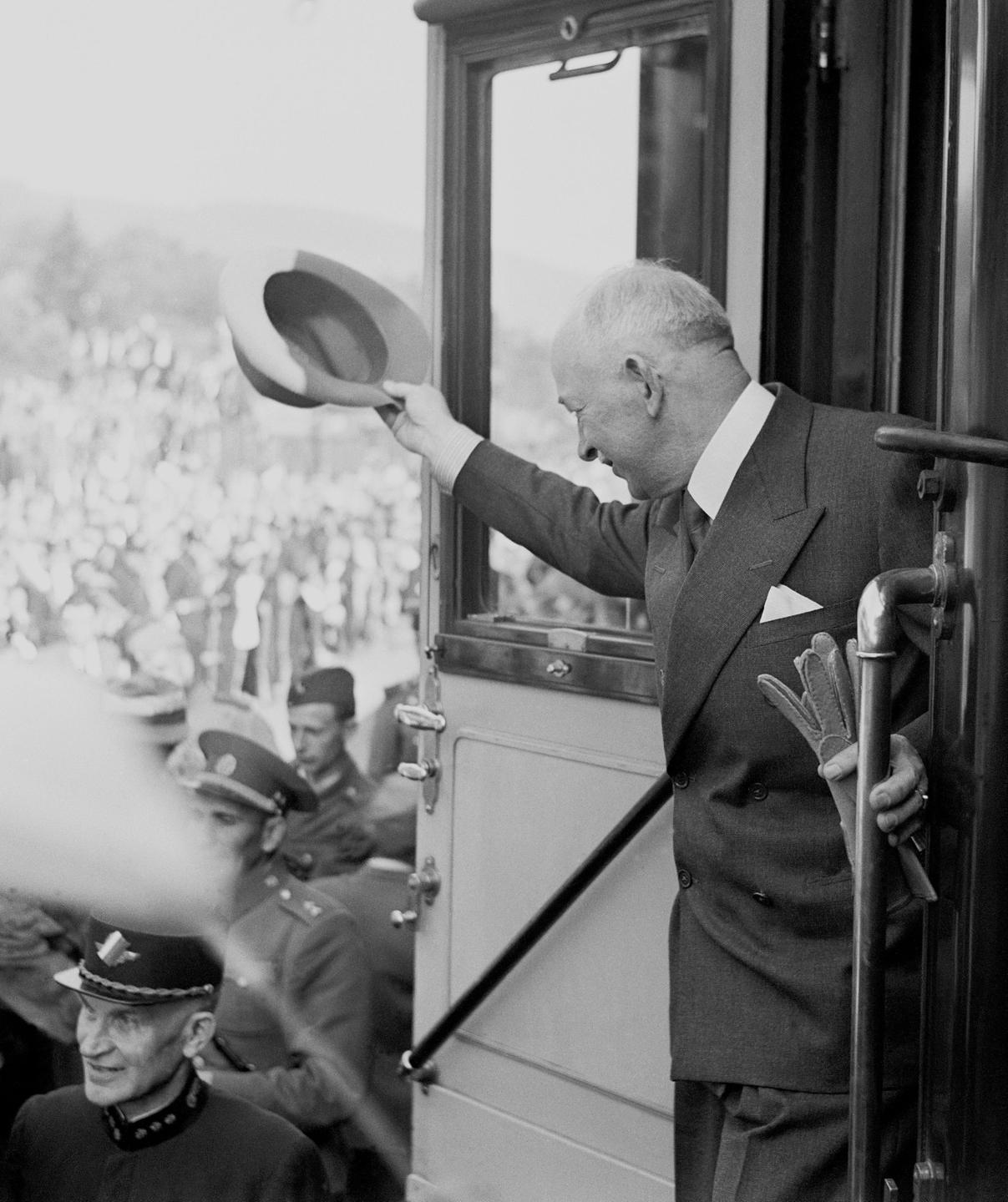 Historisches Foto von Edvard Beneš, einem älteren Mann im Anzug, der aus einem Zug heraus einer Menschenmenge zuwinkt. Historisches Foto von Edvard Beneš, einem älteren Mann im Anzug, der aus einem Zug heraus einer Menschenmenge zuwinkt.