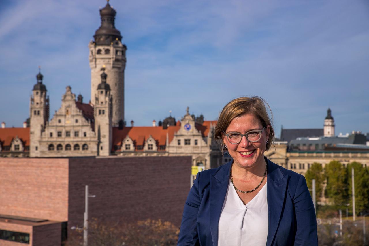 Leipzigs Kulturbürgermeisterin Skadi Jennicke steht auf einem Hausdach, hinter ihr eine Stadtkulisse.