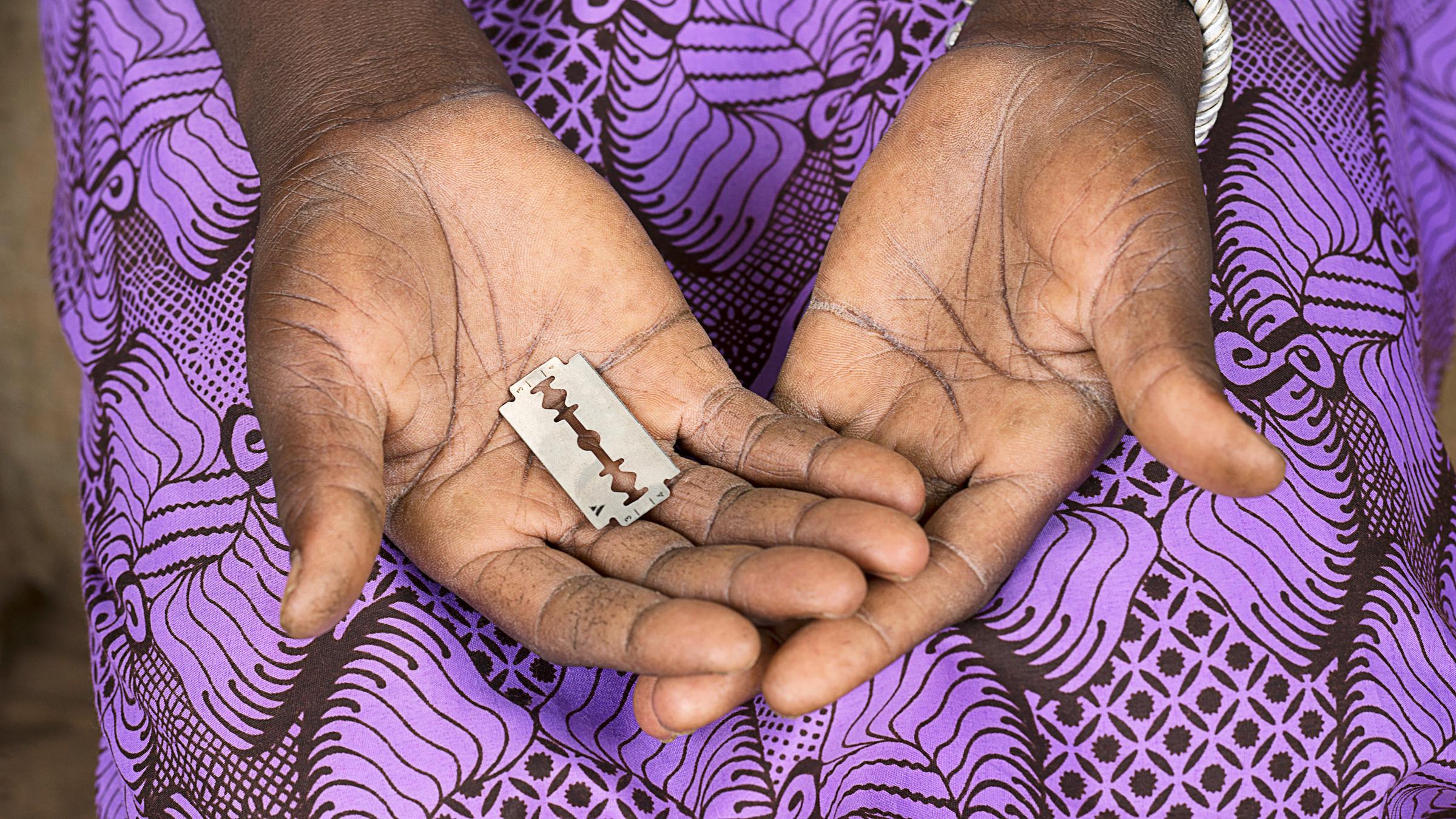 Eine PoC hält eine Rasierklinge in der Hand. Sie trägt ein ein violettfarbenes Kleid.