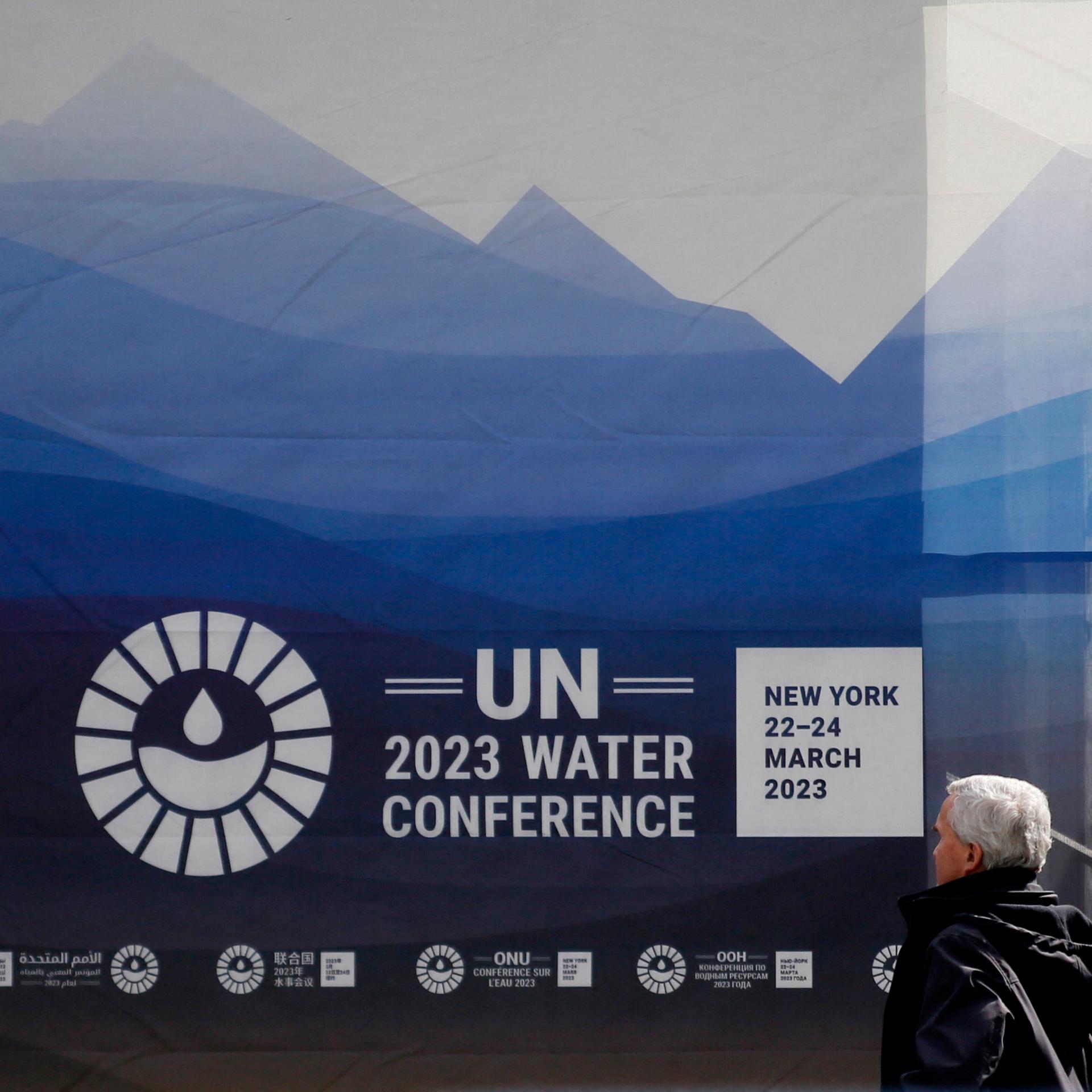 Ein Mann läuft in New York am UNO-Hauptsitz vorbei, man sieht das Logo der UNO-Wasserkonferenz.