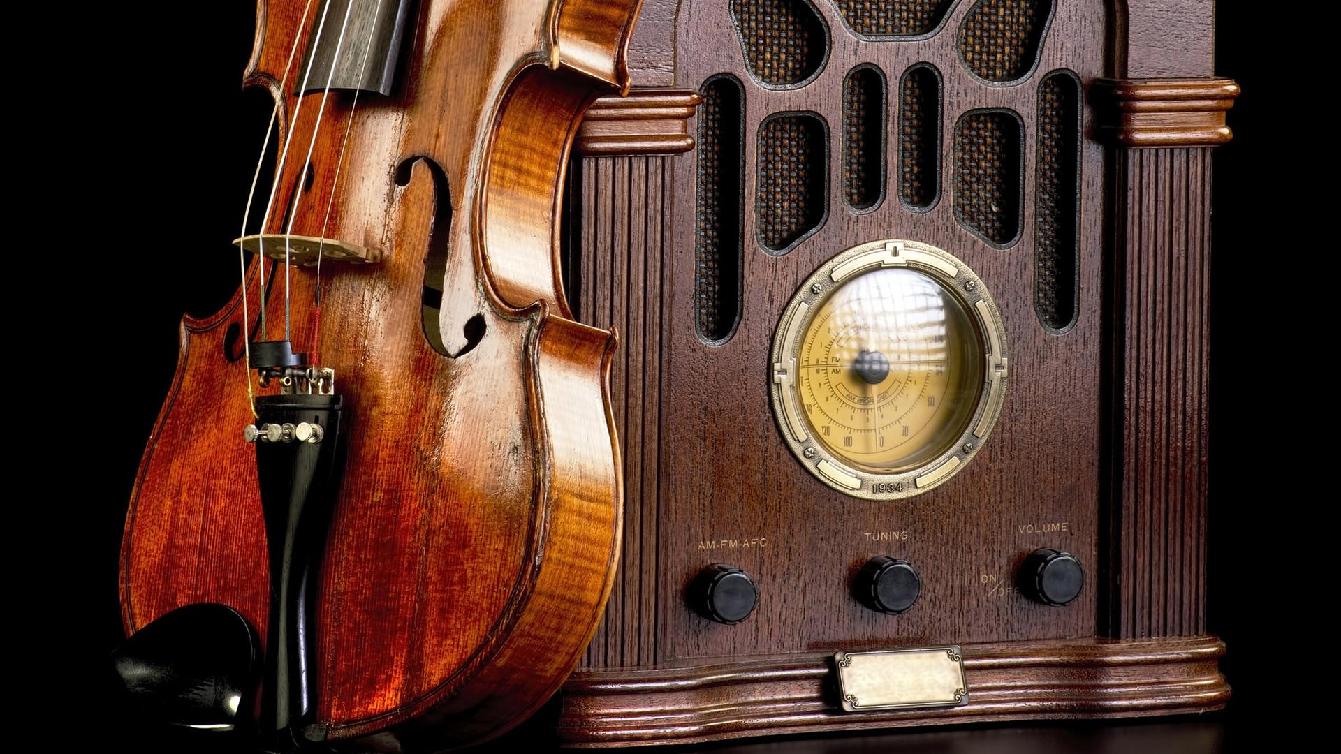 An einem historischen Radio lehnt eine Violine. An einem historischen Radio lehnt eine Violine.