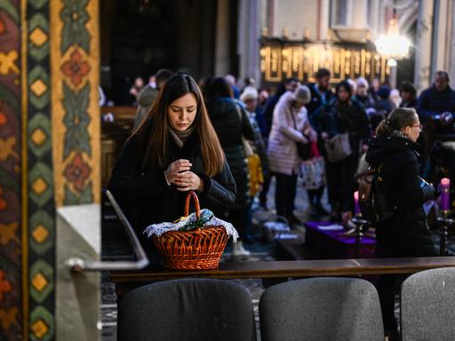 Eine Frau während der Segnung mit ihrem Osterkorb in einer Kirche der ukrainischen Stadt Lwiw.