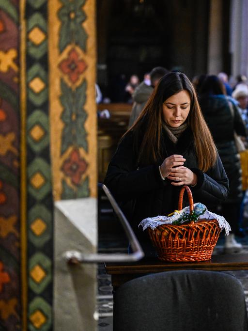 Eine Frau während der Segnung mit ihrem Osterkorb in einer Kirche der ukrainischen Stadt Lwiw.
