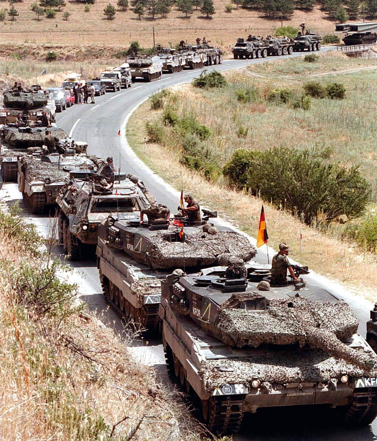 Ein deutscher Militärkonvoi mit "Leopard"-Panzern an der Spitze wartet am 12.6.1999 an der mazedonisch-jugoslawischen Grenze auf den Marschbefehl. Auf den Fahrzeugen sitzen Soldaten. Daneben teilweise deutsche Fahnen.