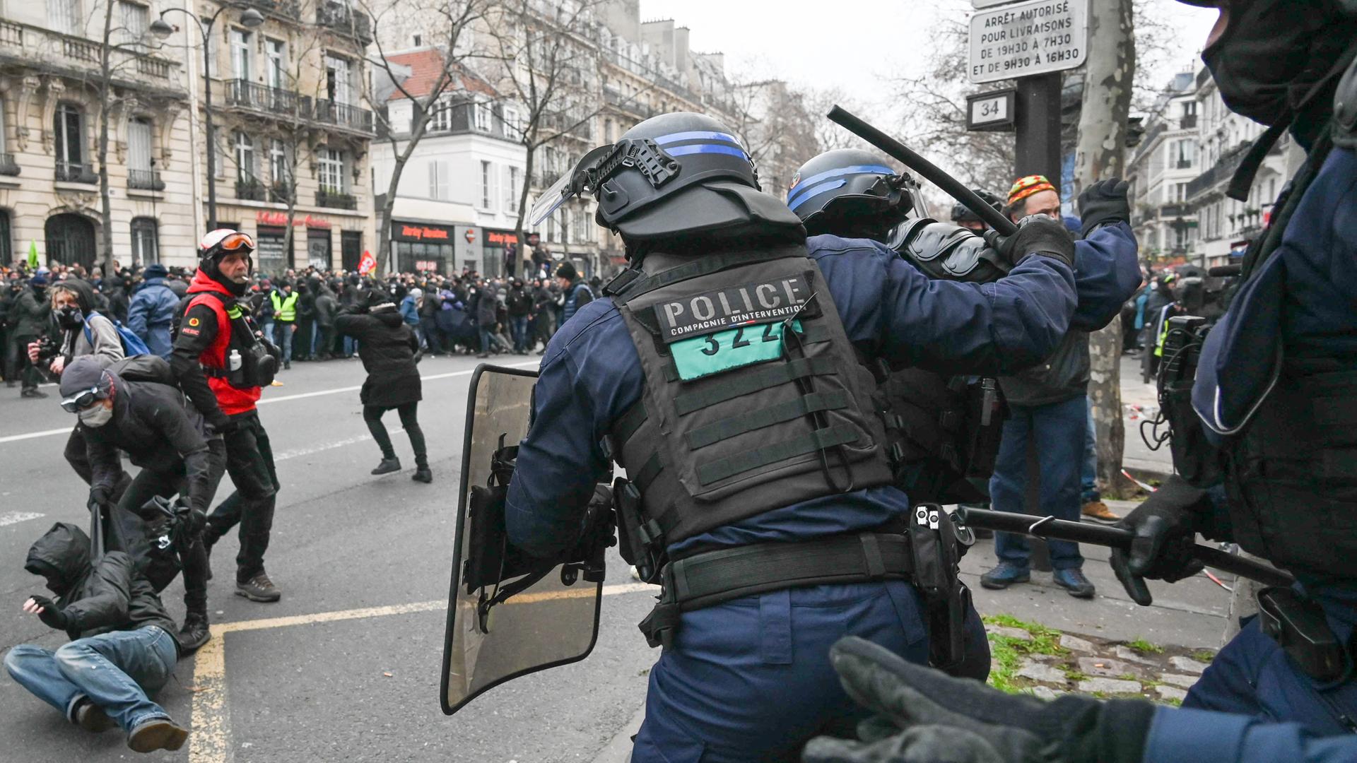 Ein französischer Polizist in Paris hebt einen Schlagstock