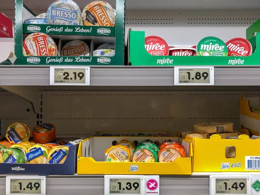 In einem Supermarkt-Regal sind Käse. Die Preise für die Waren sind hoch. 