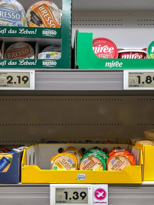 In einem Supermarkt-Regal sind Käse. Die Preise für die Waren sind hoch. 